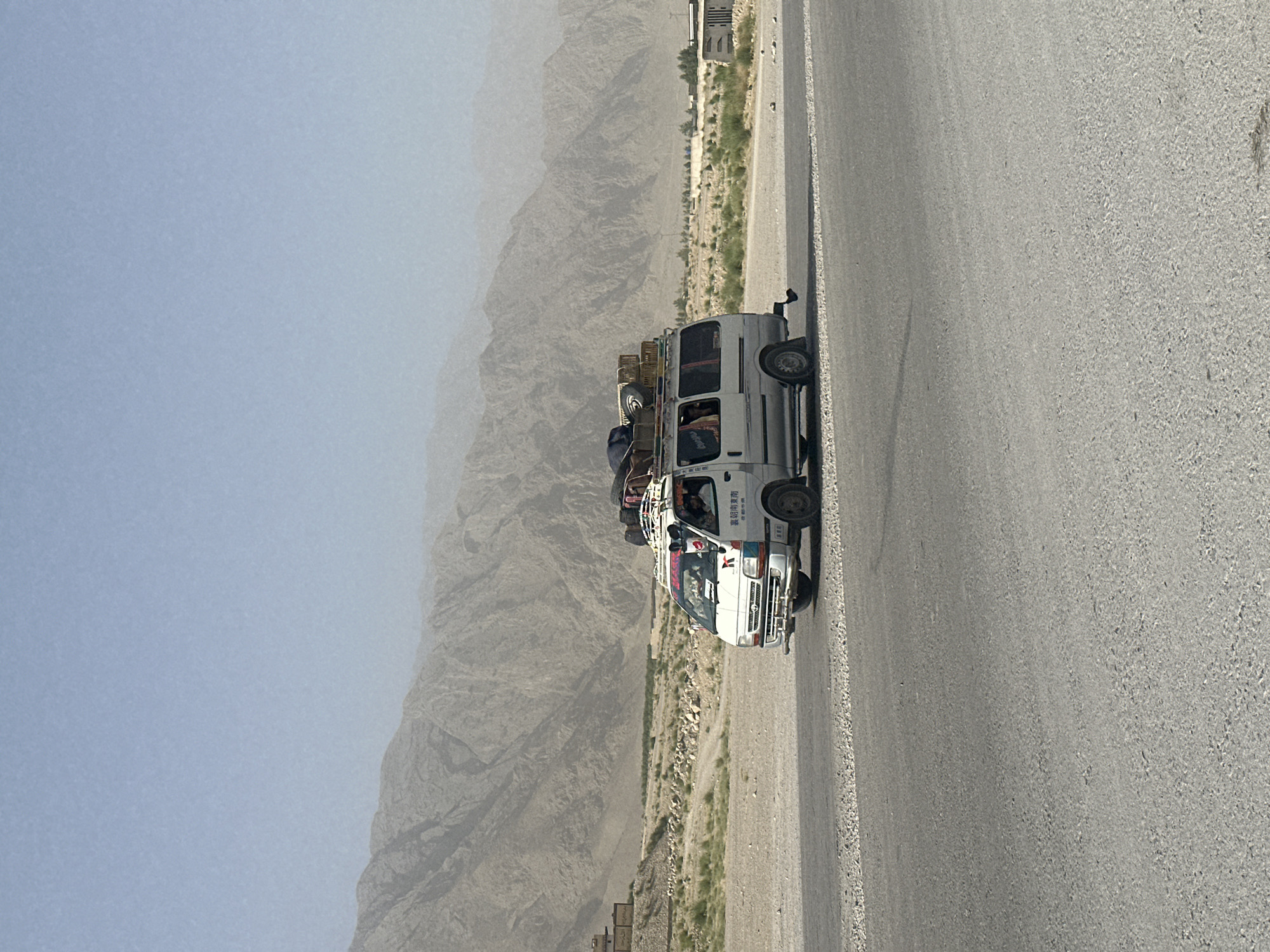 Loaded passenger van travels through arid Pakistani landscape
