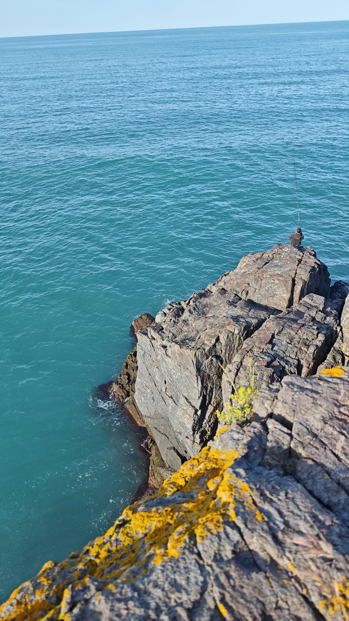 Angler fishes from rocky cliff on Bulgarian Black Sea coast
