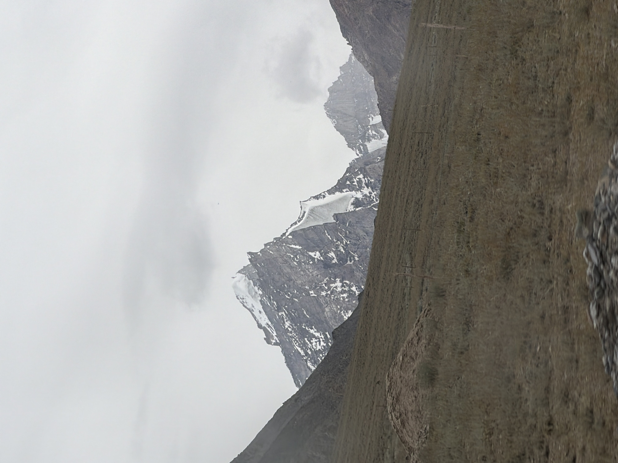 Barren mountain slope with wire fence under cloudy skies, Pibiting