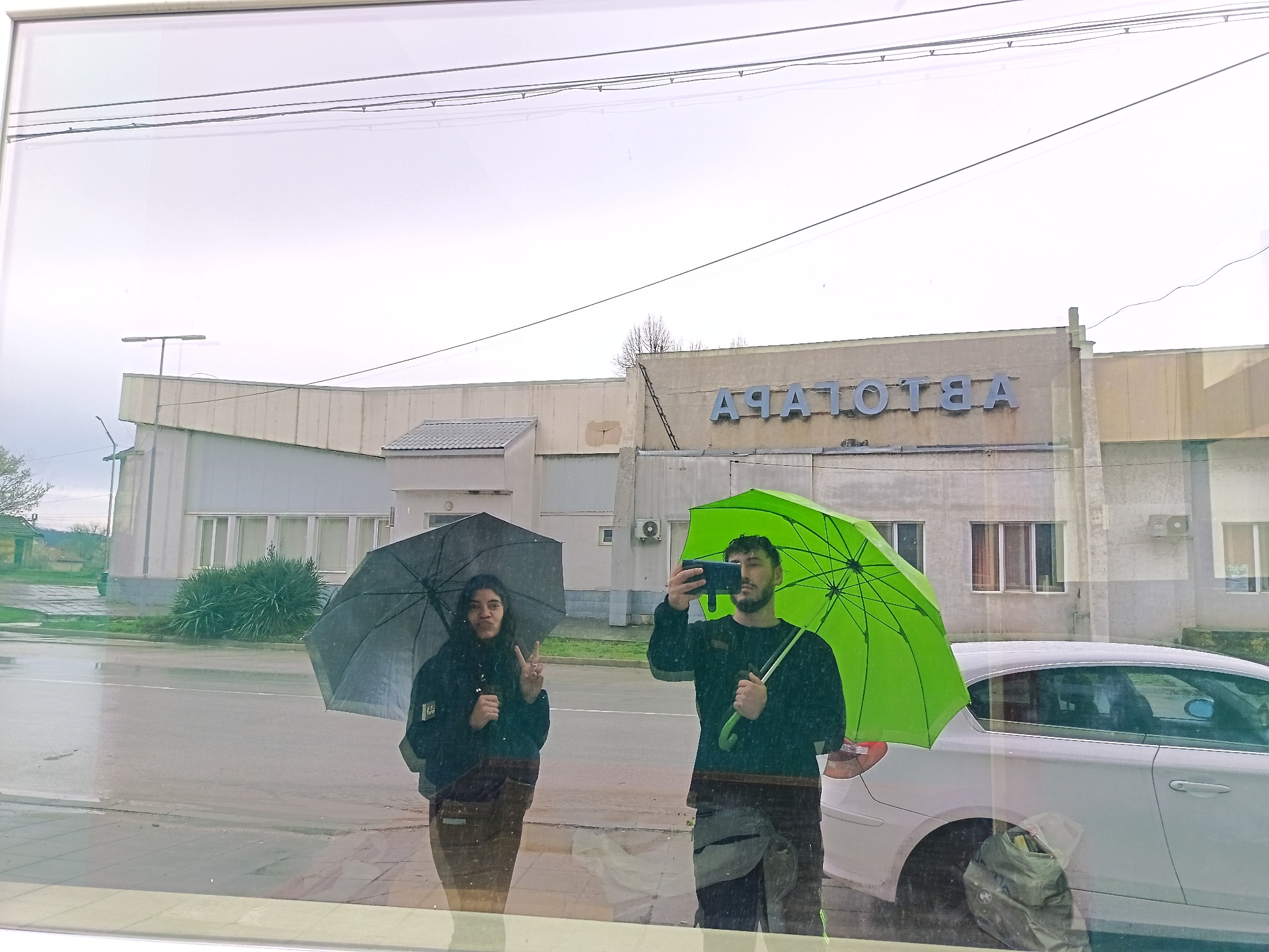 Pair with umbrellas pose by car in Roman, Bulgaria