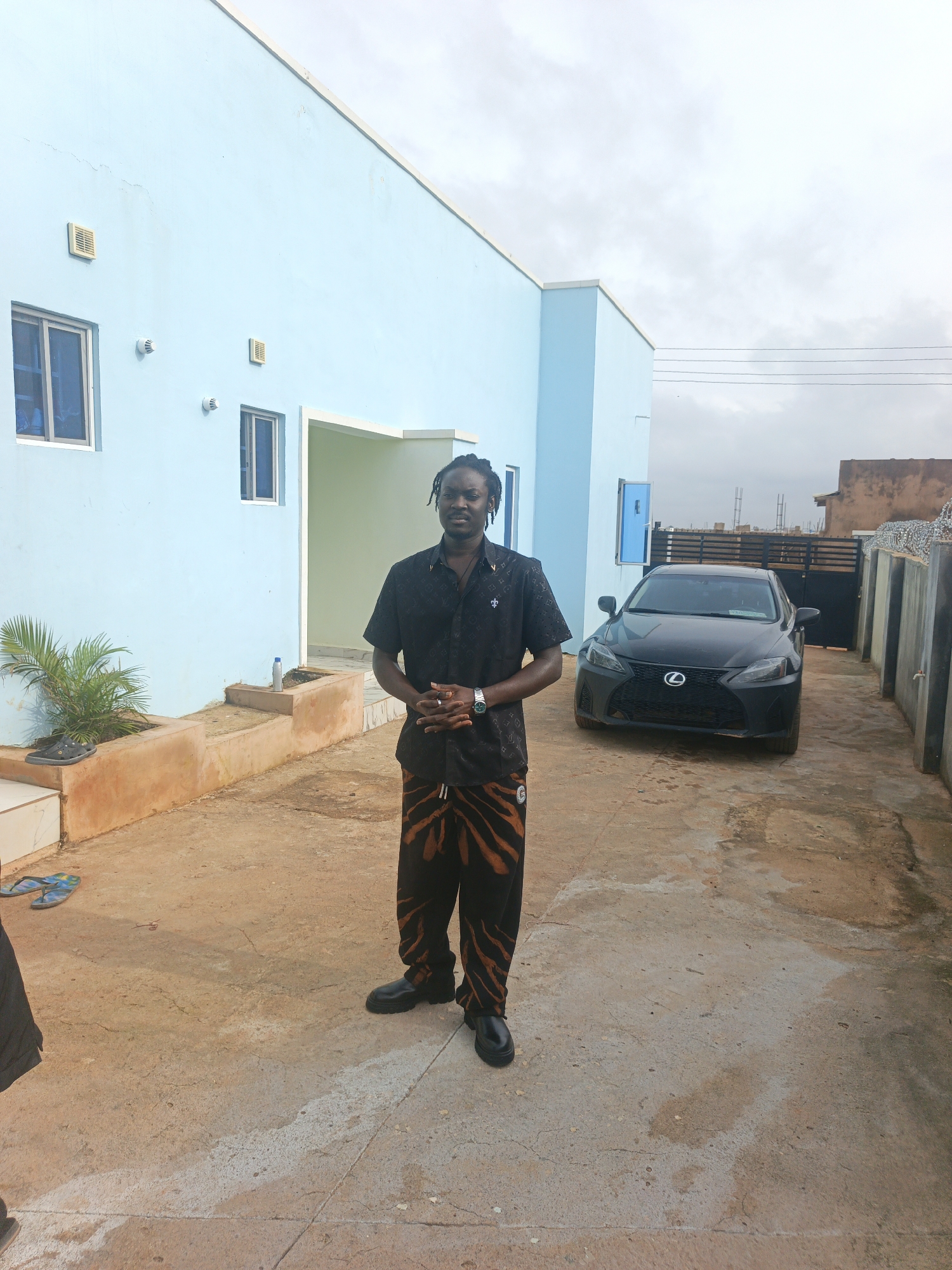 Paved driveway pause outside a light blue building, Nigeria