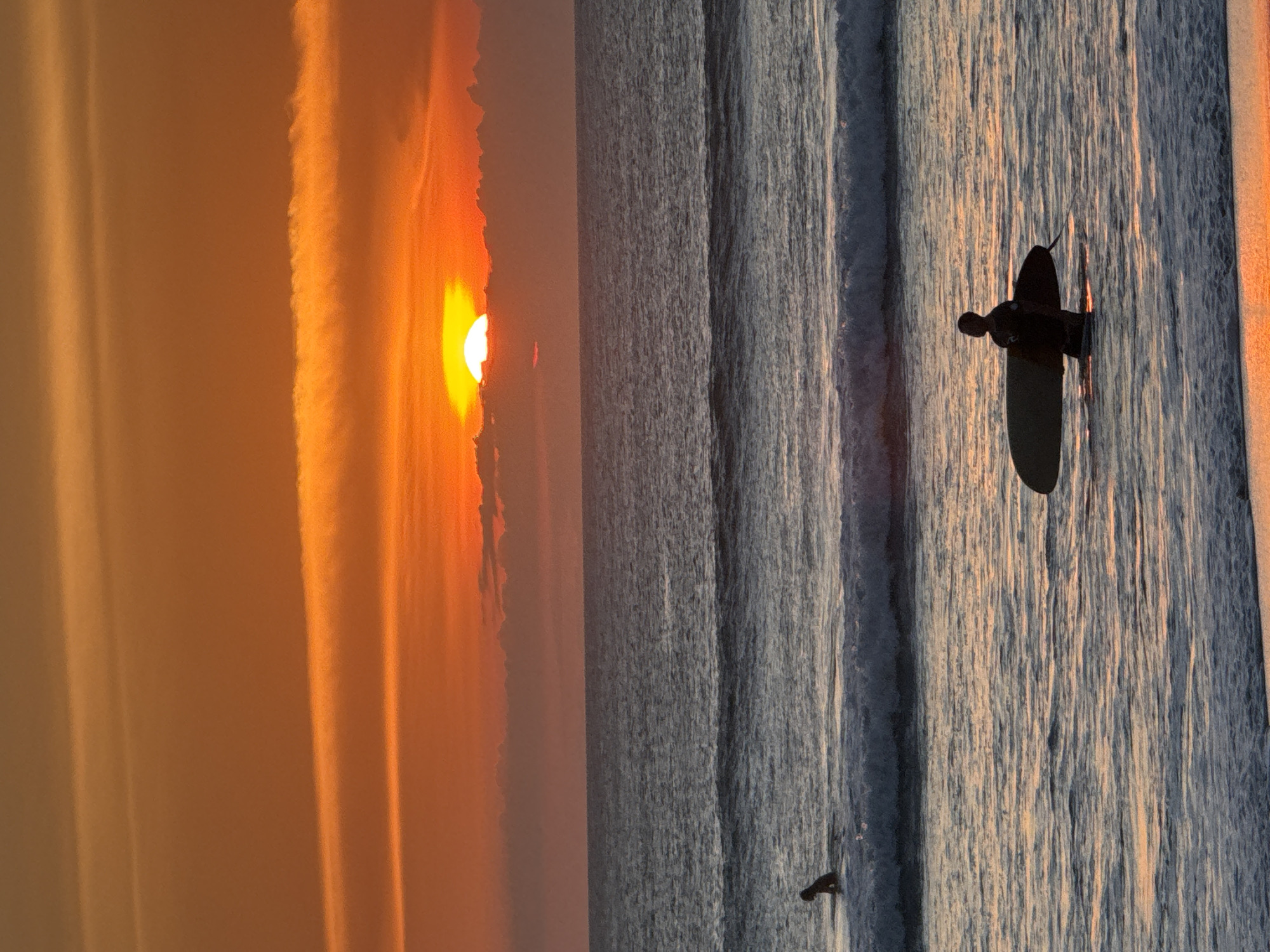 Surfer paddles at sunset in Kuta waters