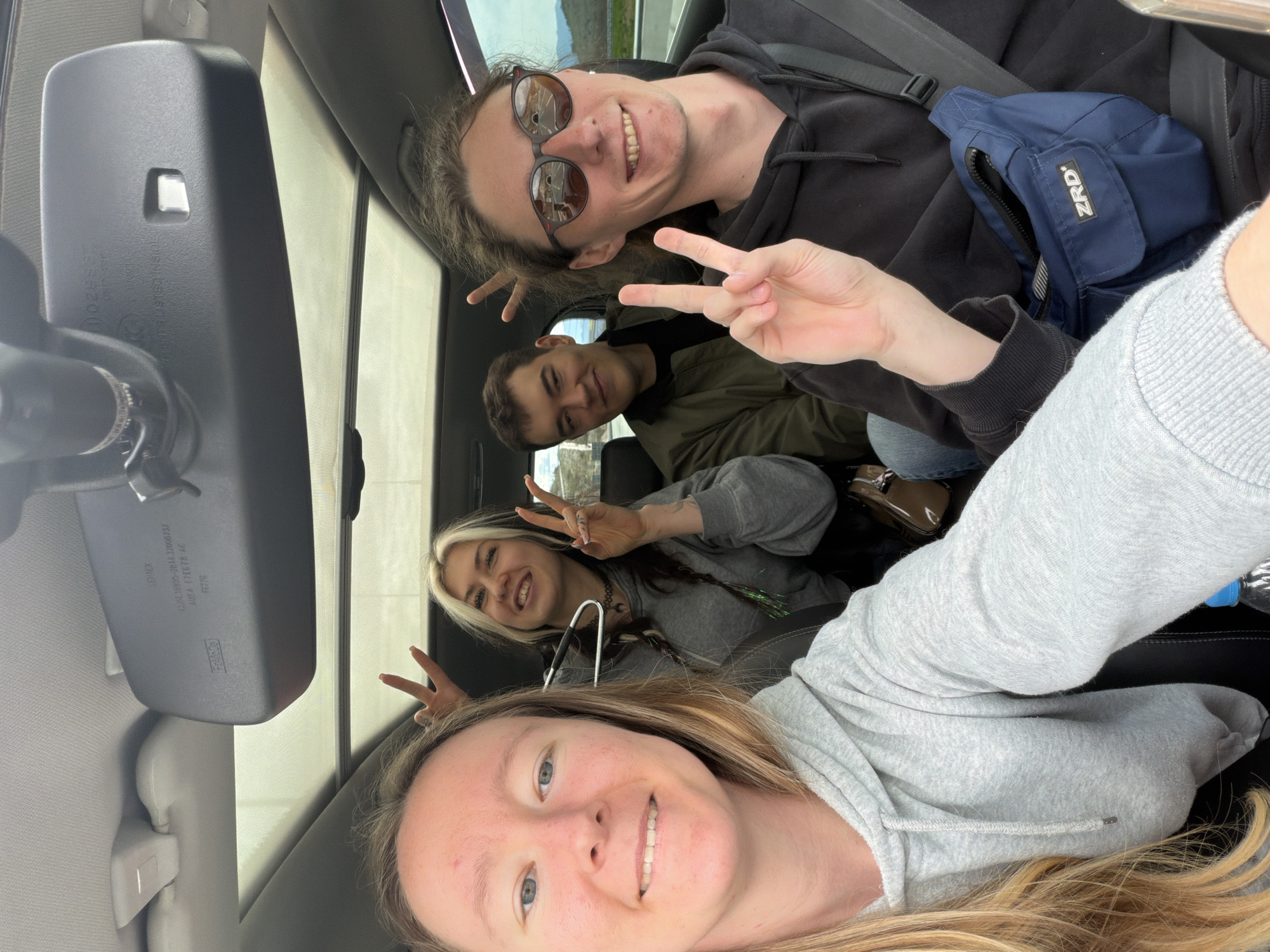 Four friends take selfie making peace signs in car