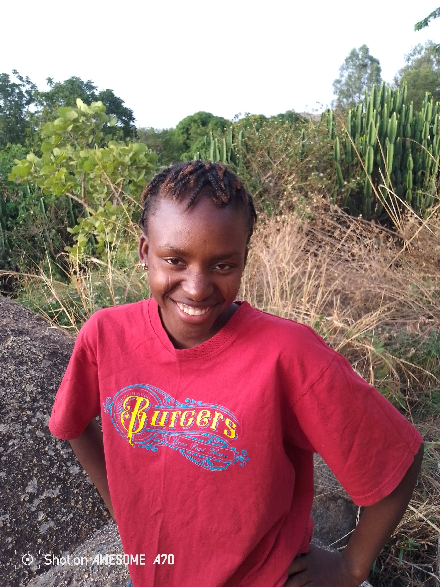 Person in red Burgers shirt photographed at desert rock formation