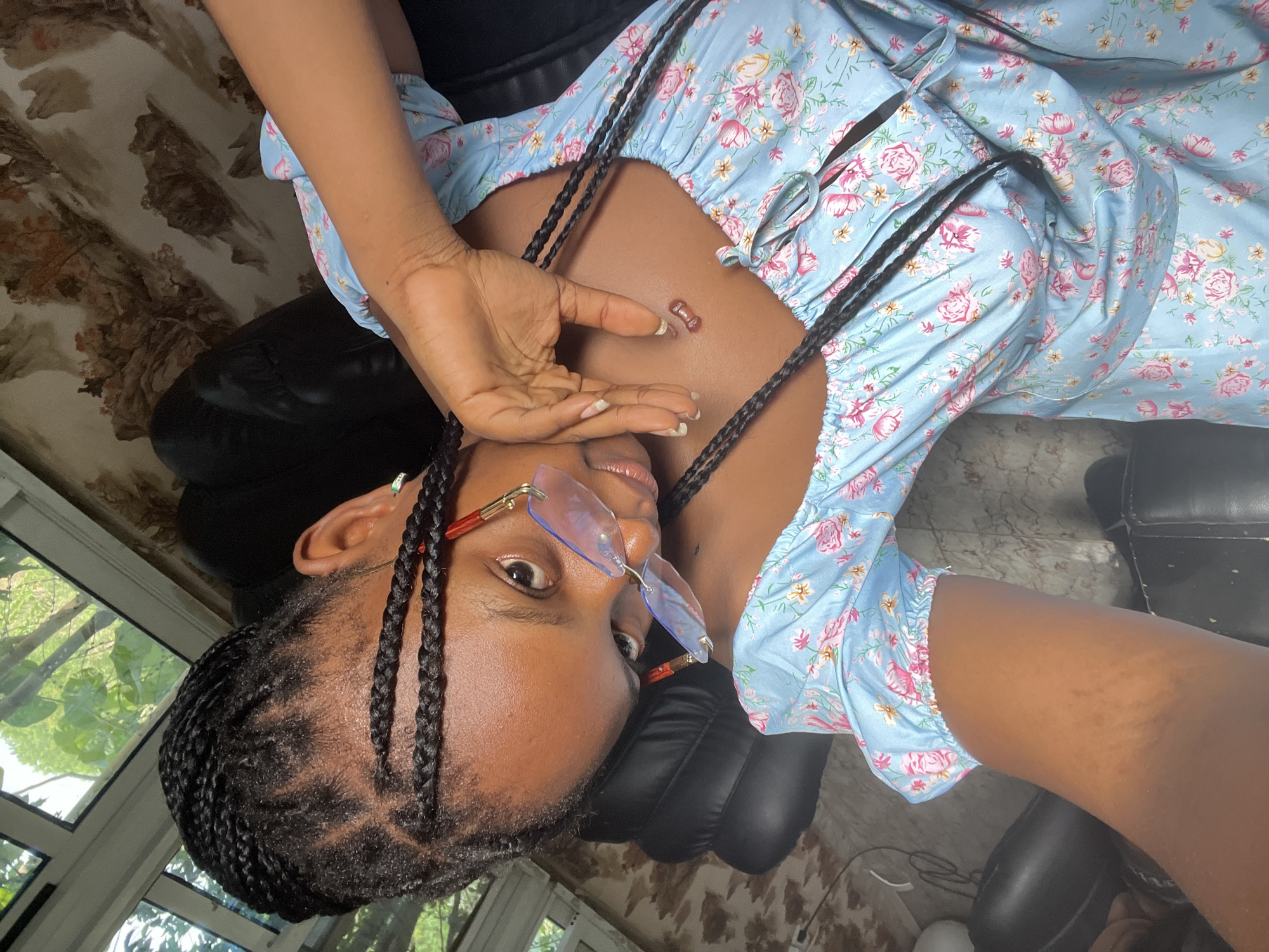 Woman in floral dress relaxes in chair, Adankolo