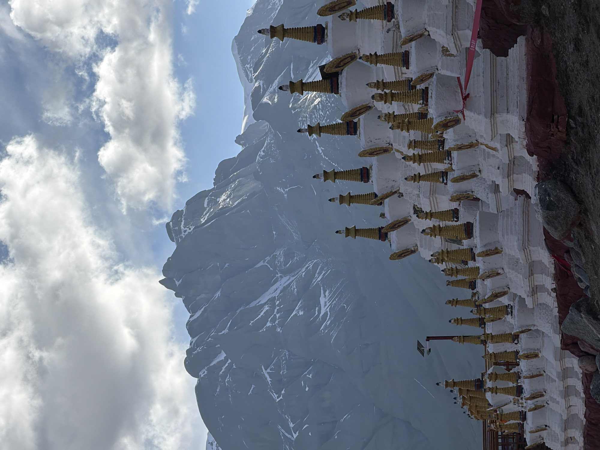Snow-capped mountains observed near golden-spired building in Parga, China