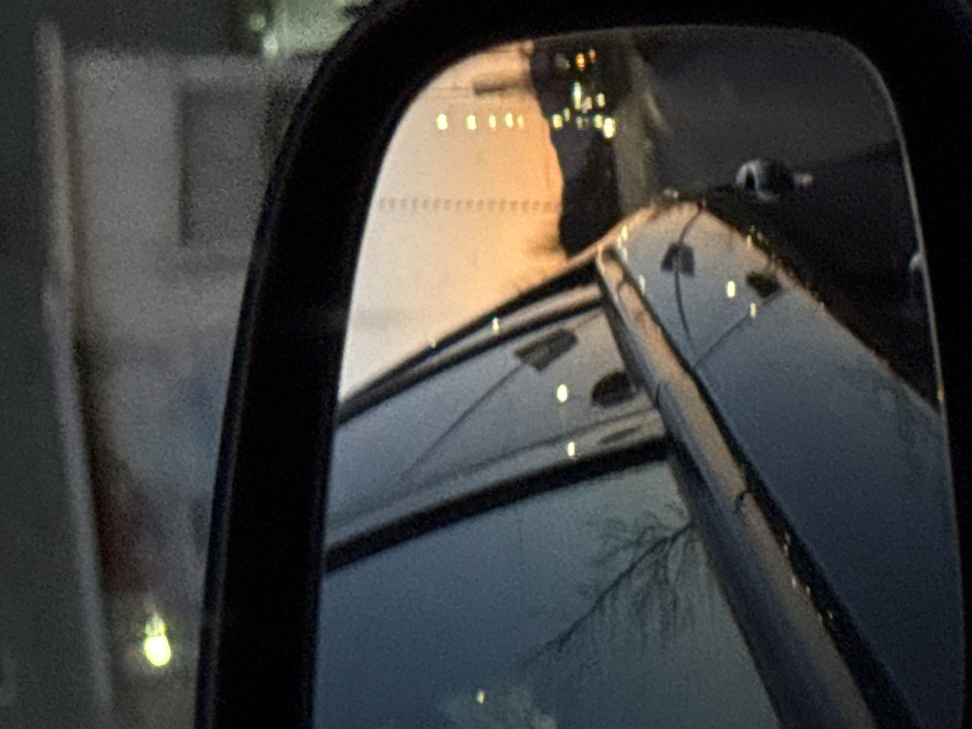 Car mirror captures nighttime street reflection in Sofia