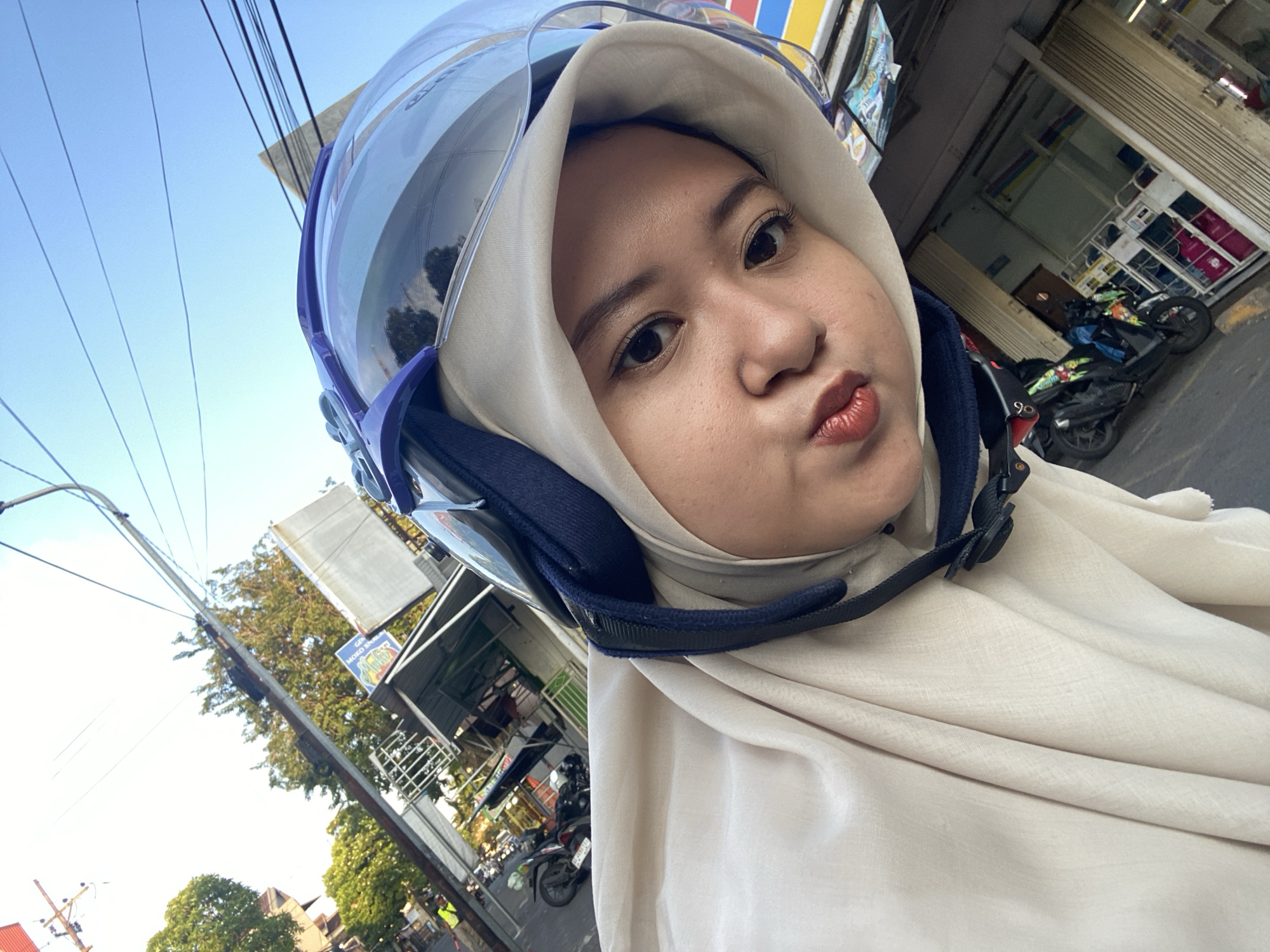 Woman takes motorcycle selfies near seafood restaurant in Sidoarjo