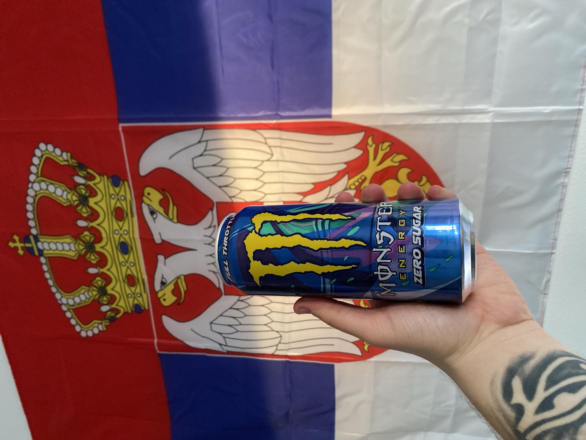 Energy drink held with Serbian flag backdrop in Subotica