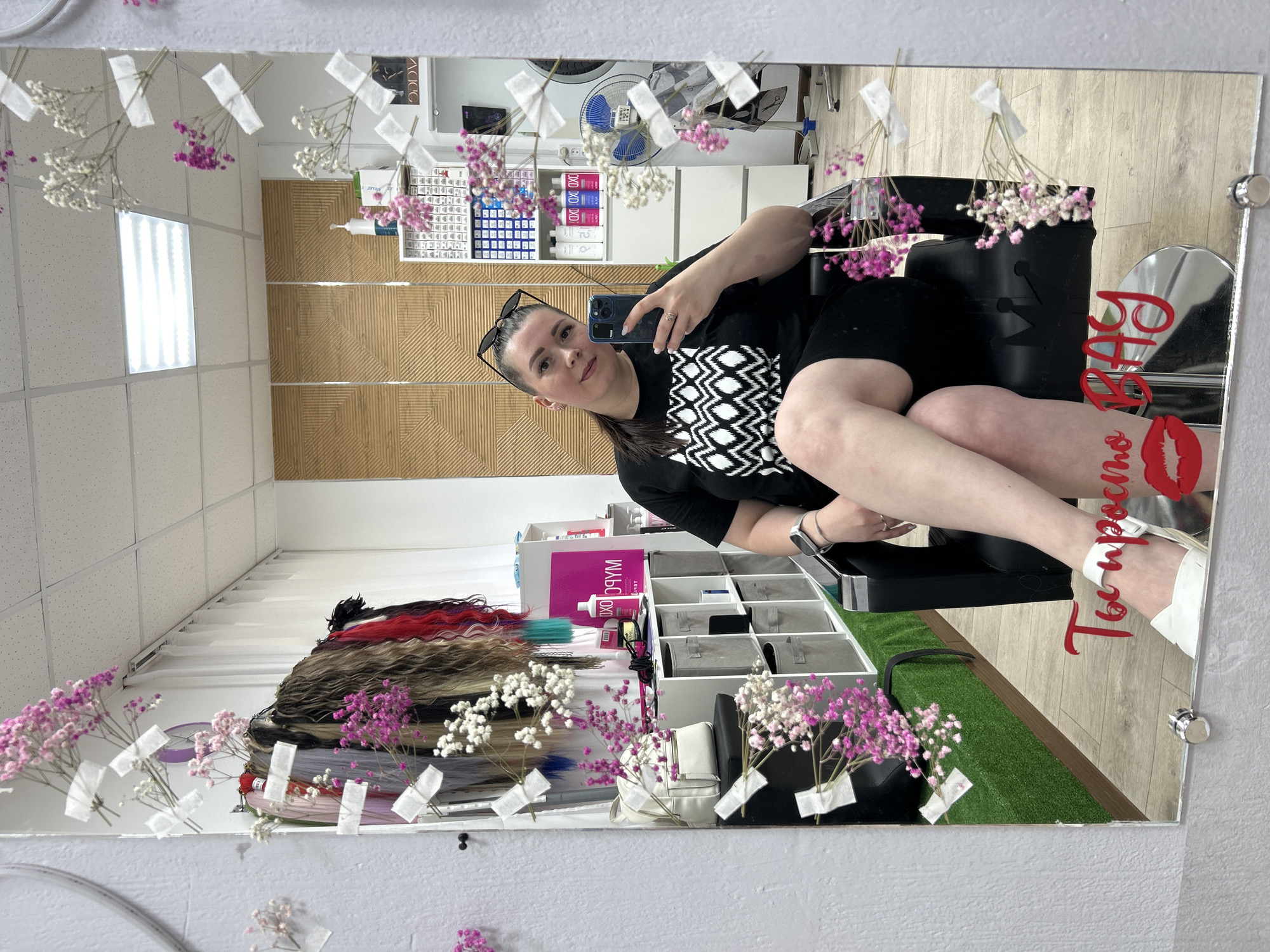 Woman takes selfie in flower-decorated salon mirror