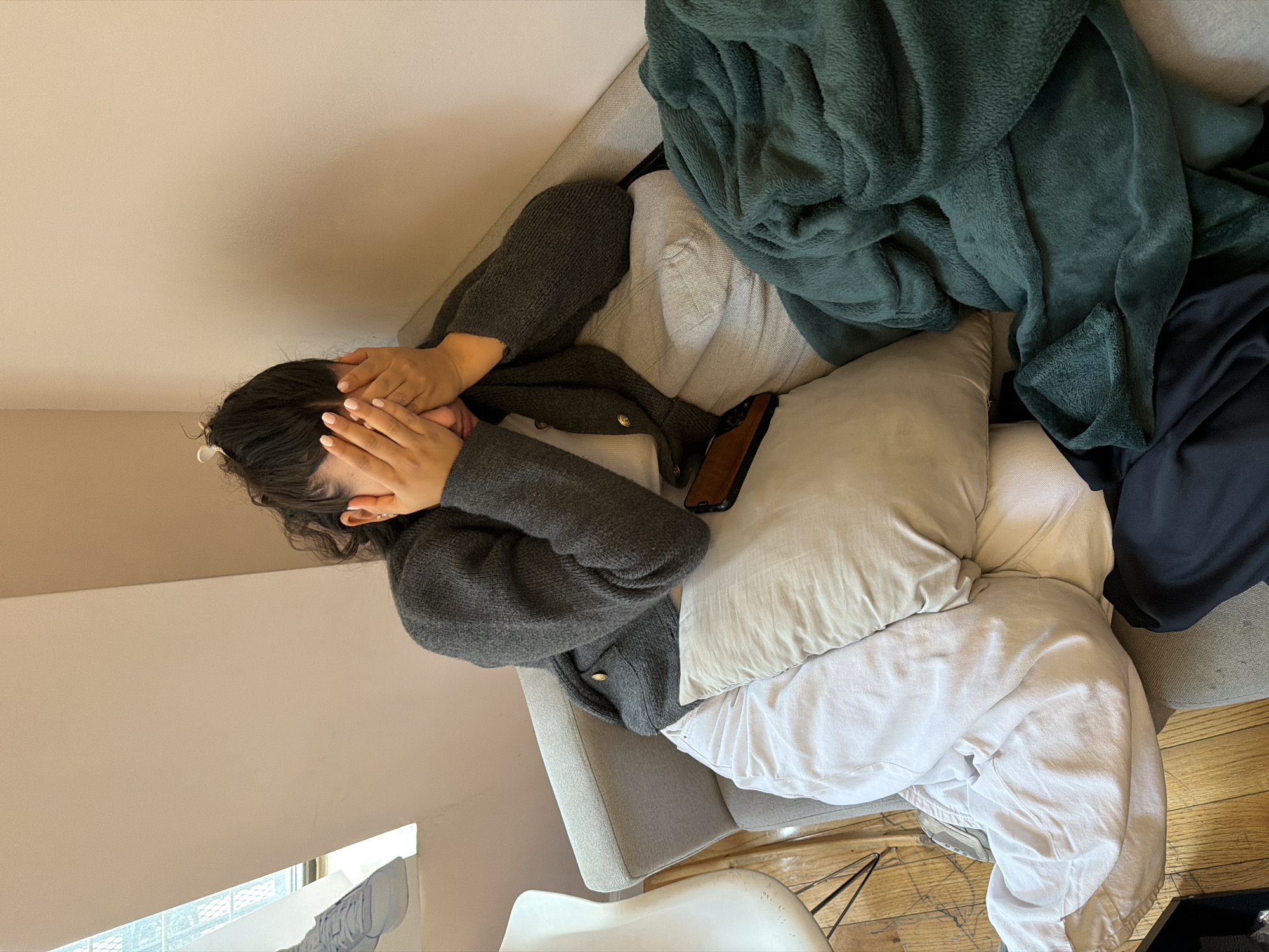 Woman lies face-down on sofa covering face in New York