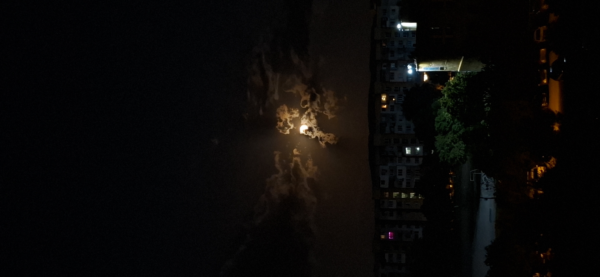 Full moon rises through dramatic clouds over Sofia at night