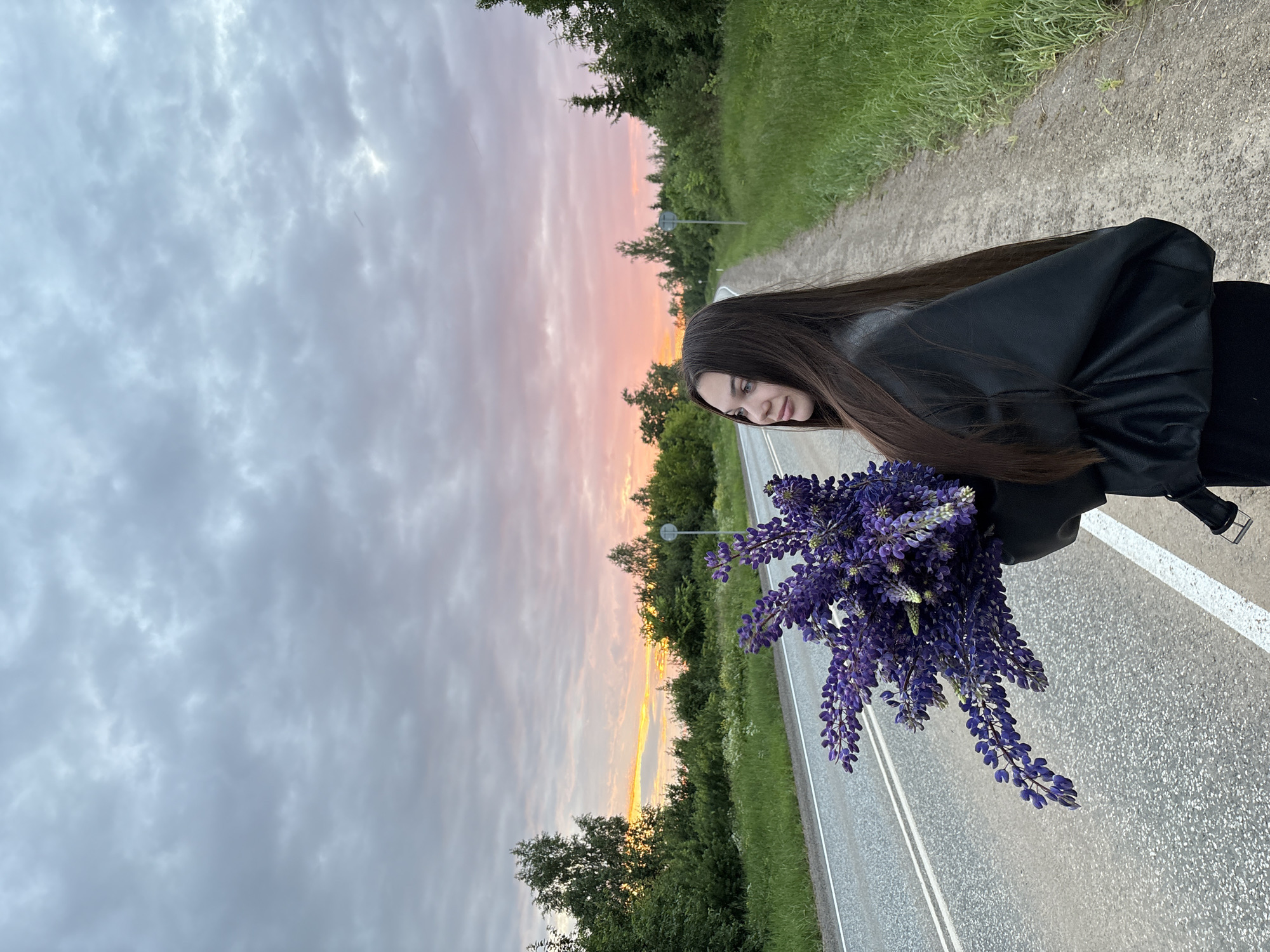 Woman holds purple lupine bouquet on roadside in Garevaya