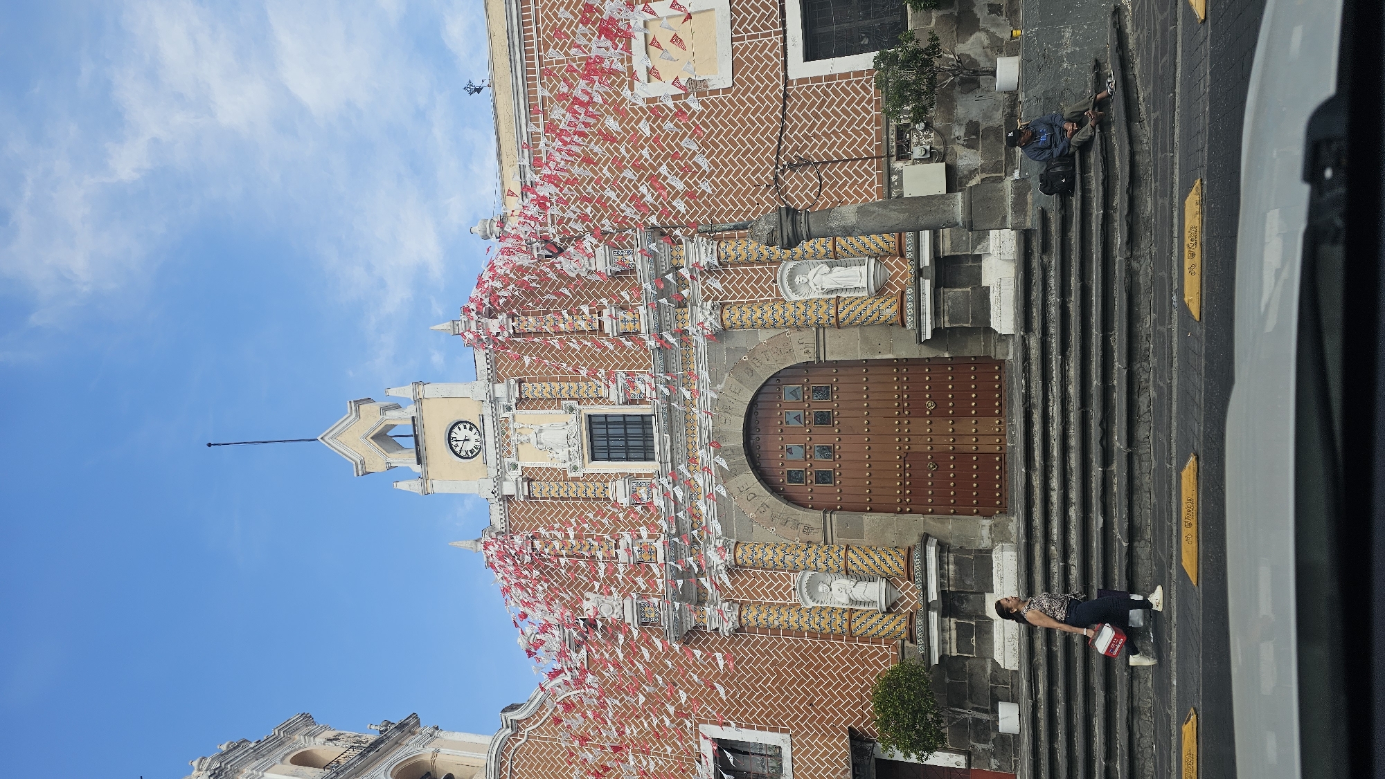 Historic Puebla church adorned with ceremonial red and white flags