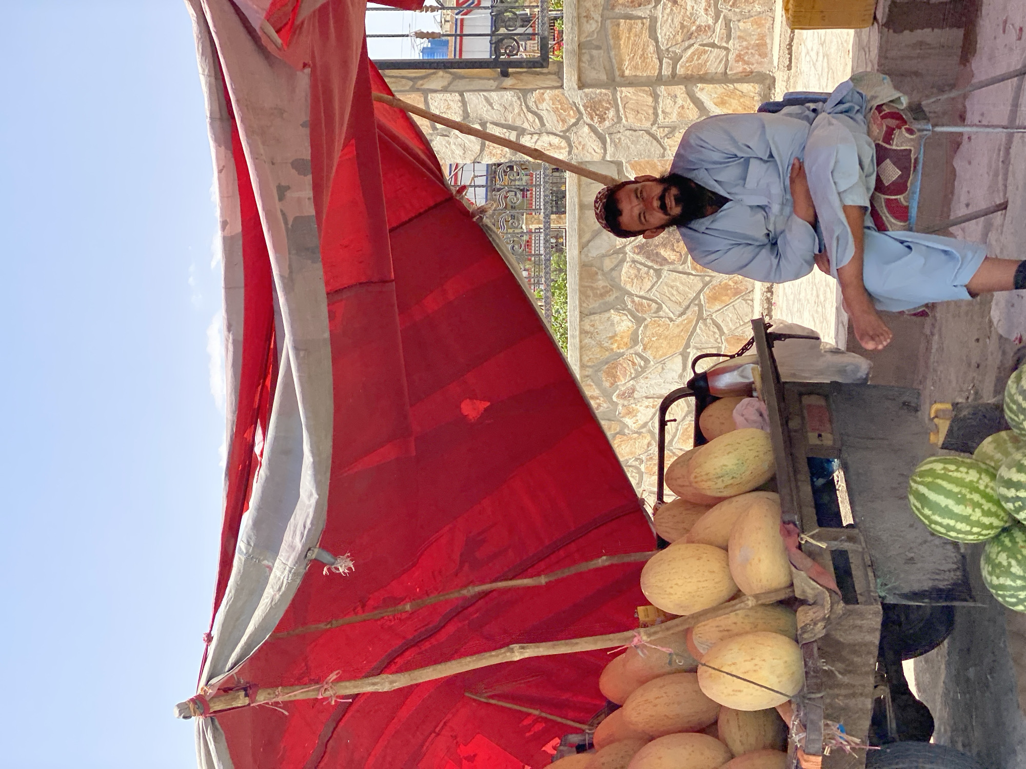 Fruit stand vendor at rest under a tarp in Kandahar