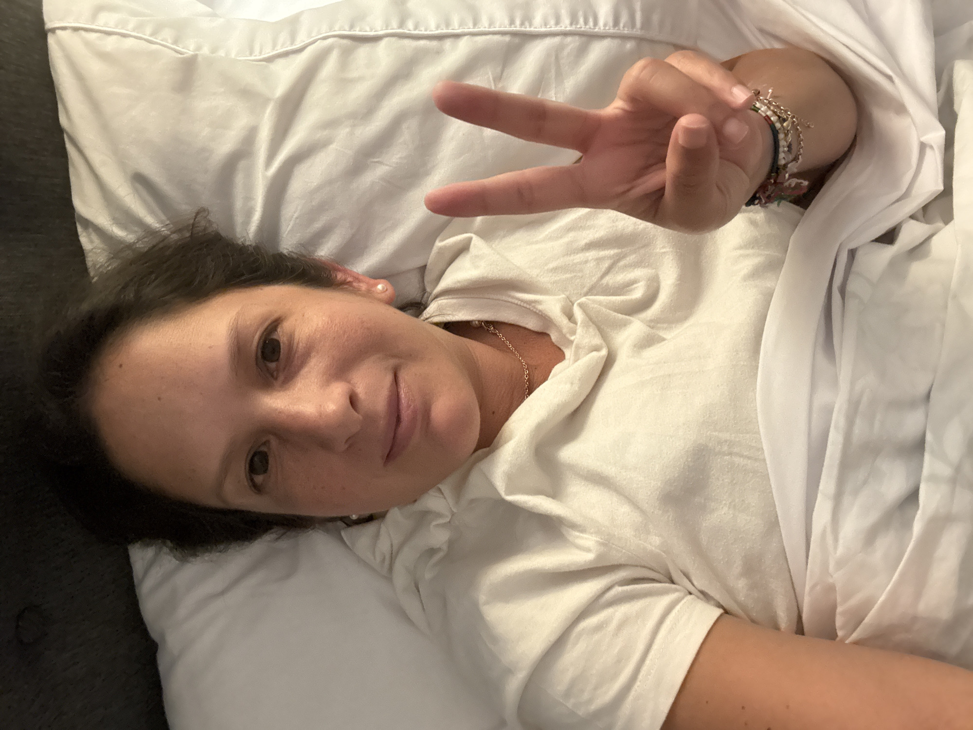 Woman makes peace sign gesture in bed in San Isidro