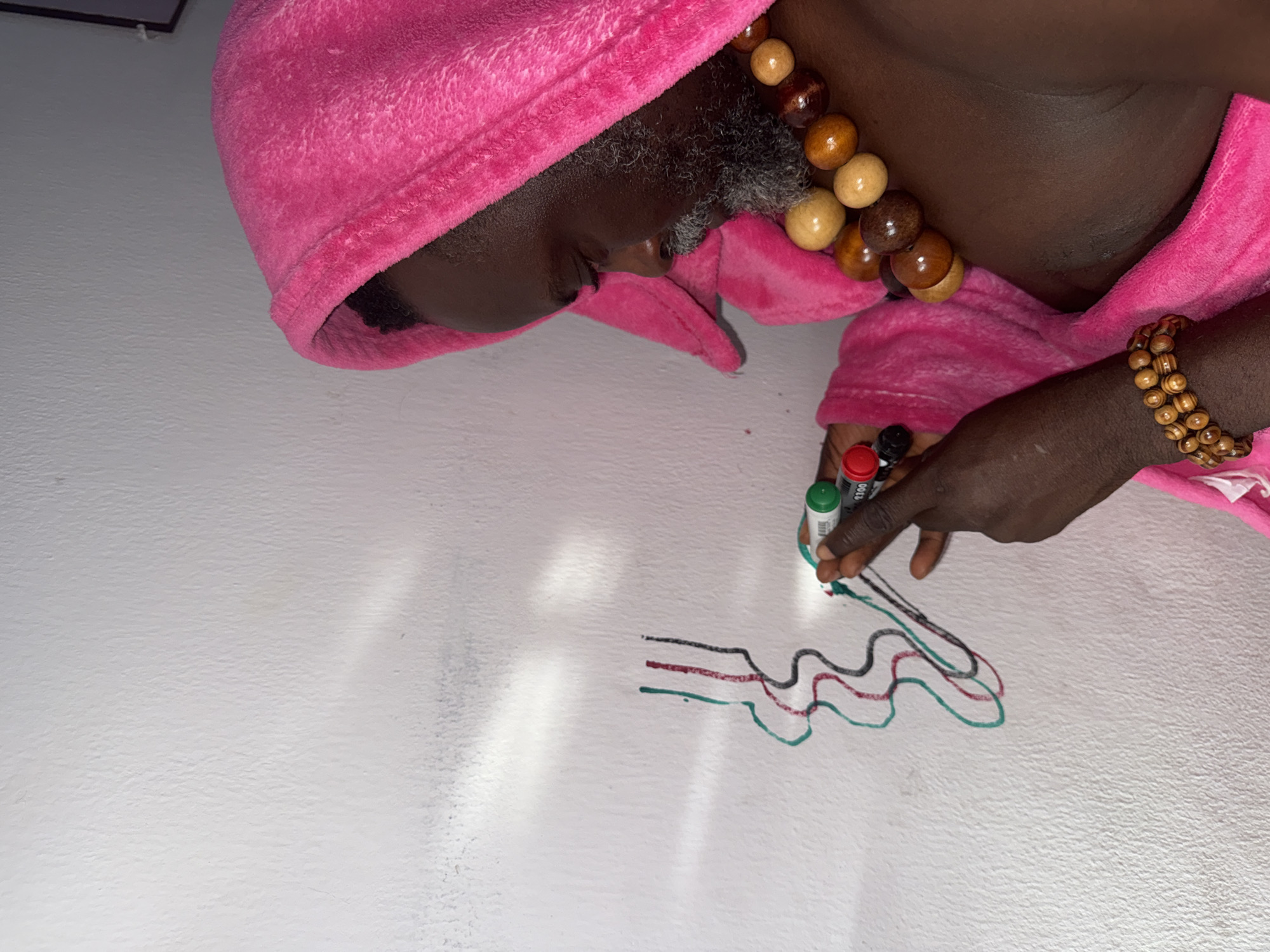 Person in pink robe creates wall art in Ado