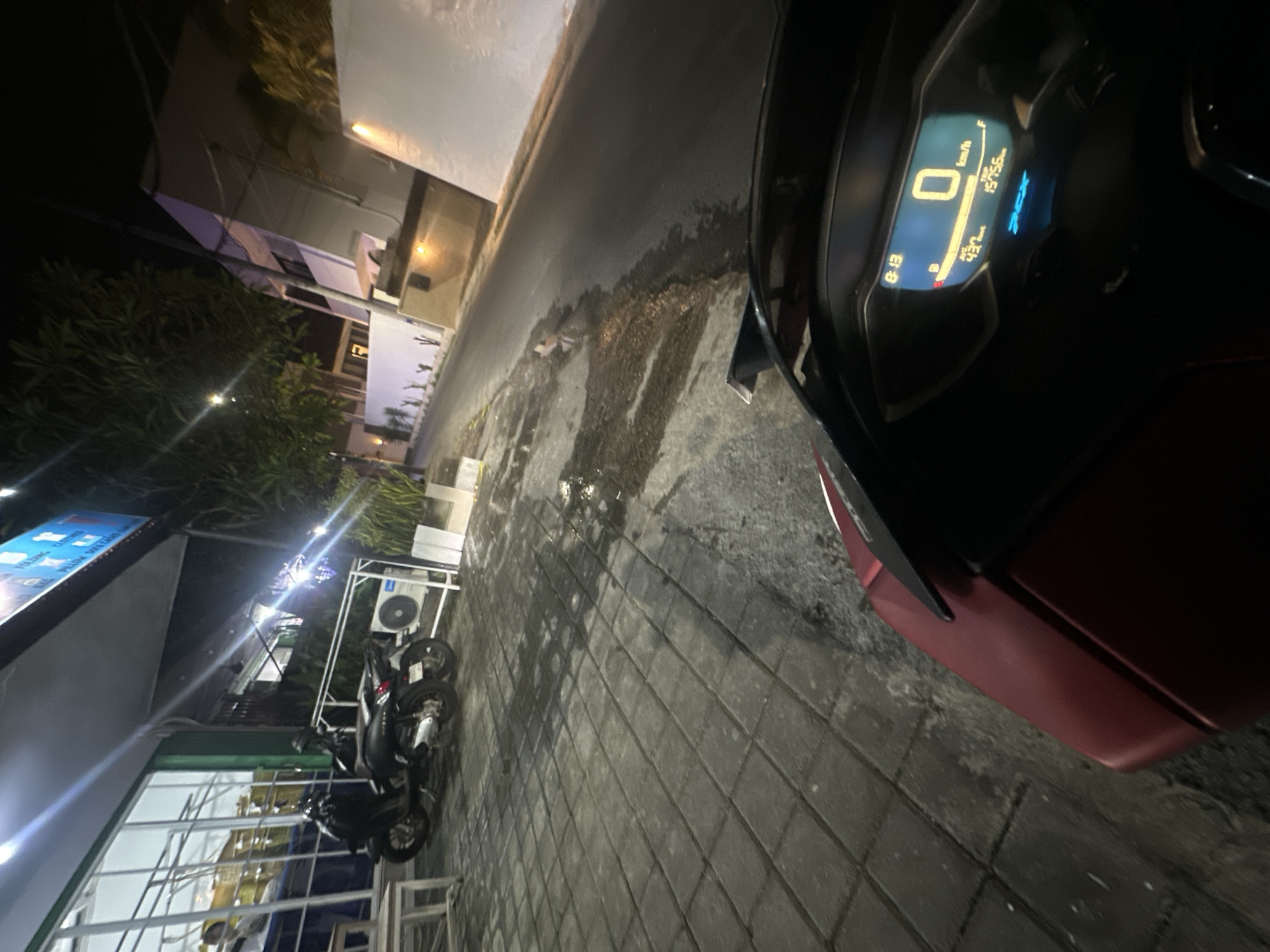 Person with red scooter pauses on North Kuta sidewalk