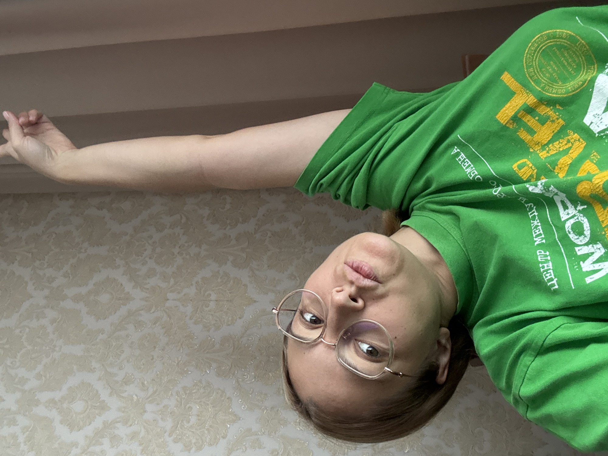 Looking up at a high-angle camera, arm raised, indoors
