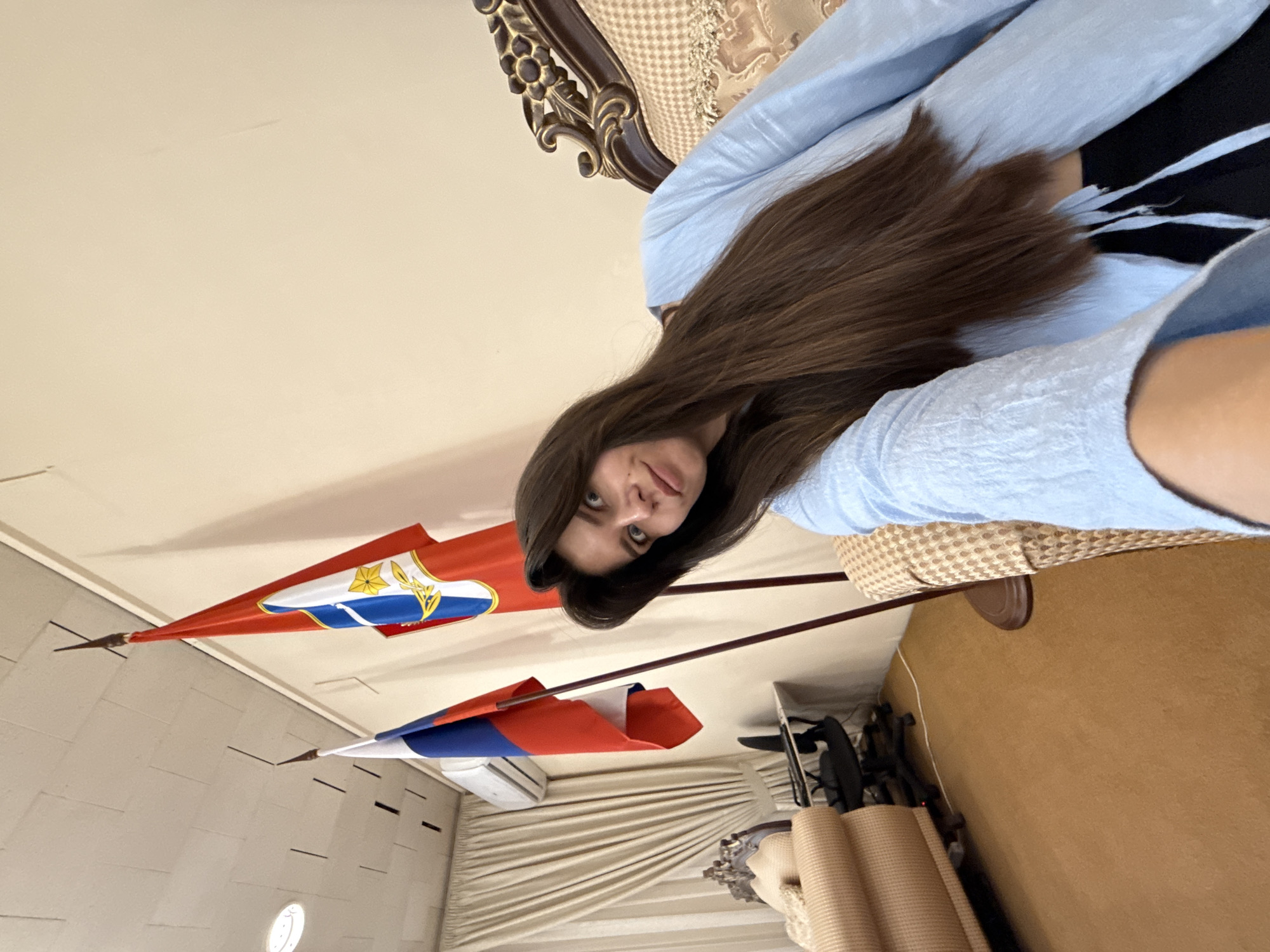 Woman takes selfies in formal diplomatic office with flags