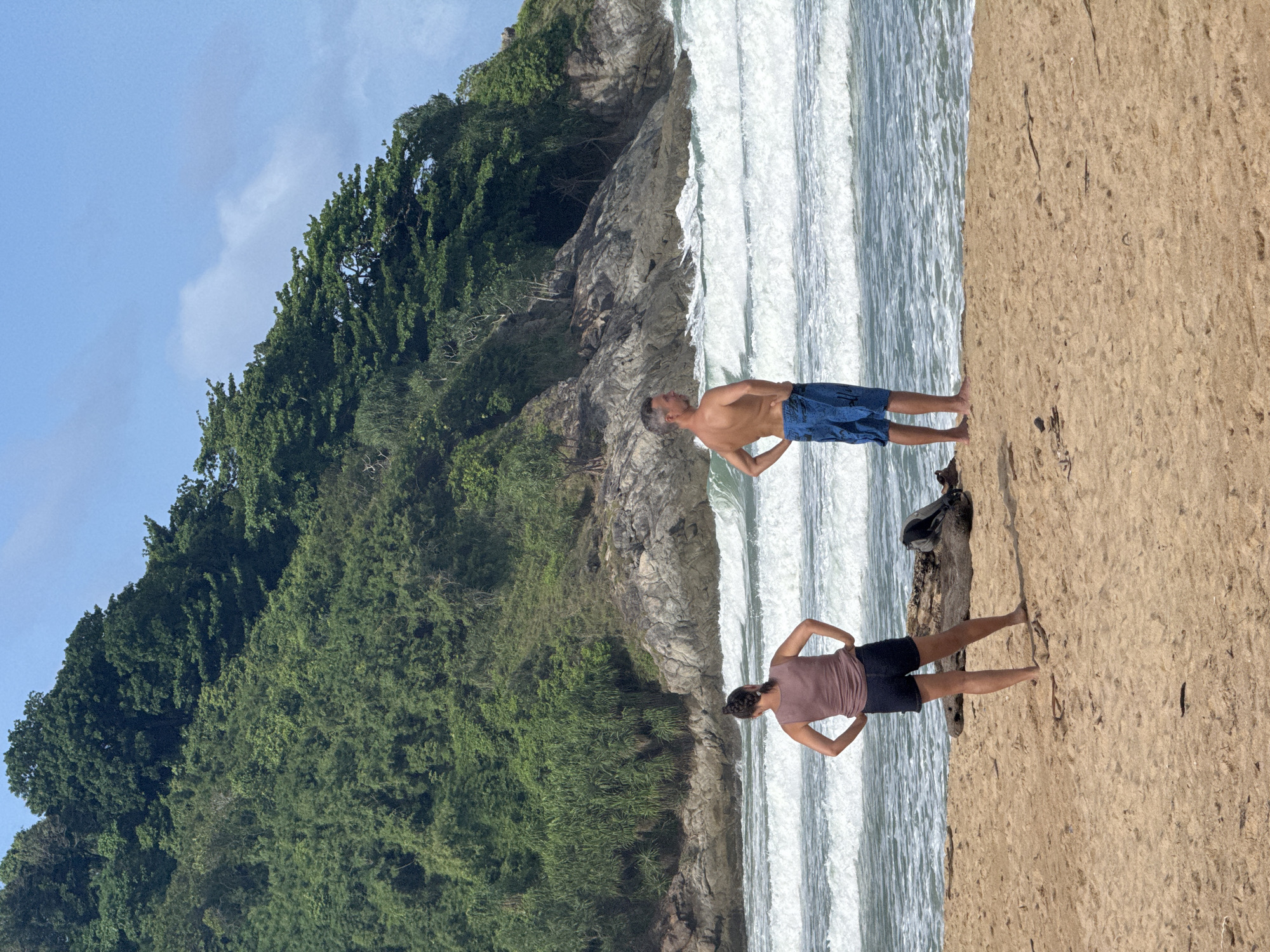 Kitesurfers and beachgoers at a flagged Rawai shoreline