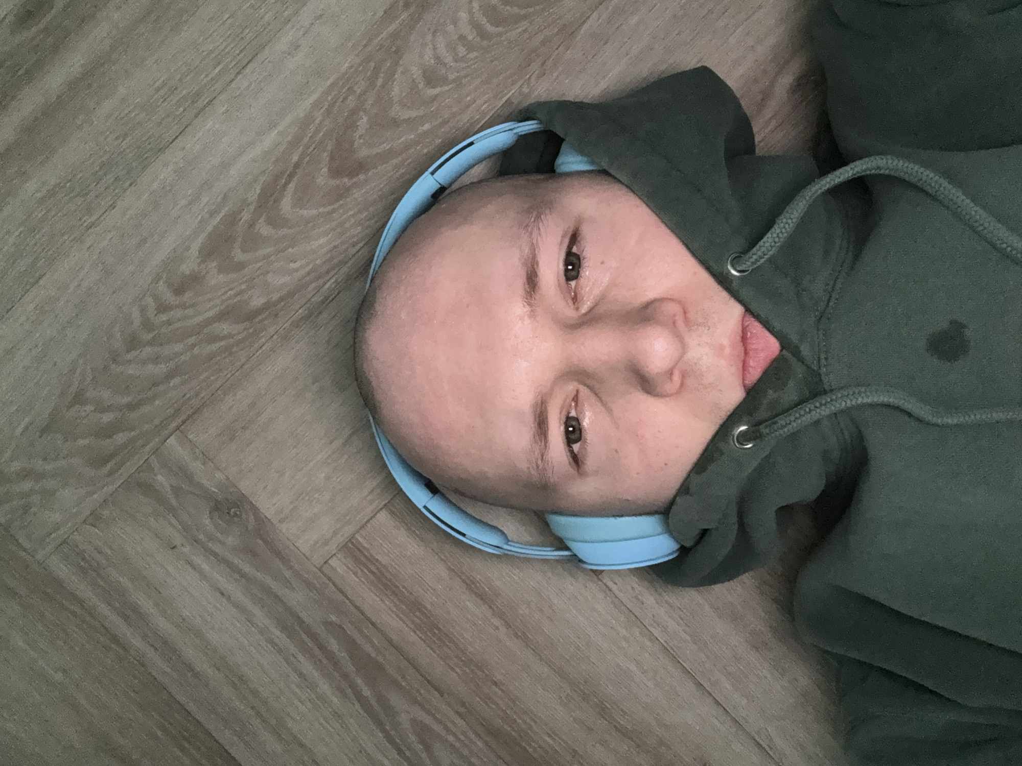 Person in headphones lies on wooden floor in Krasnoyarsk