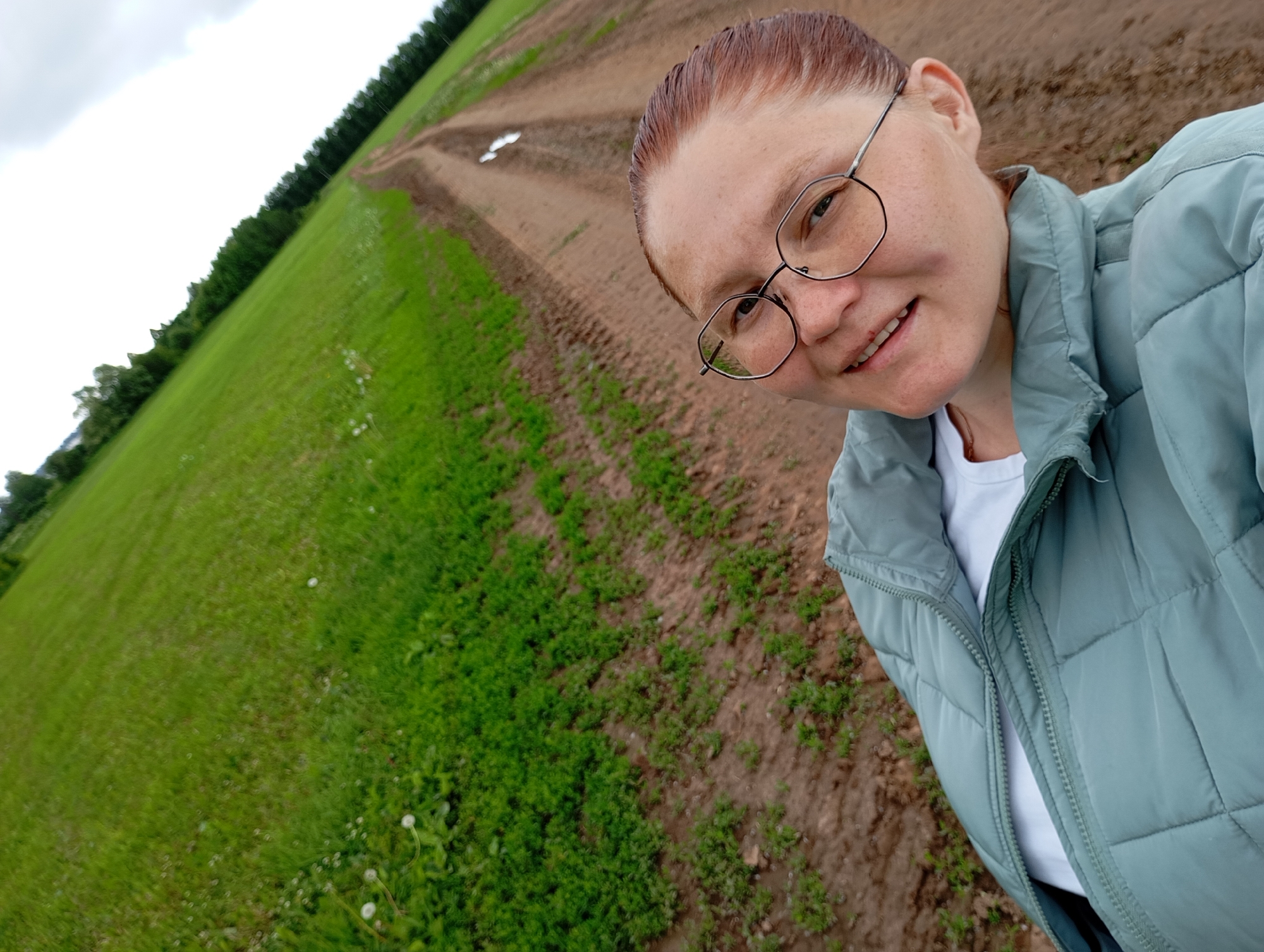 Woman takes selfies near smoking industrial buildings in rural Russia