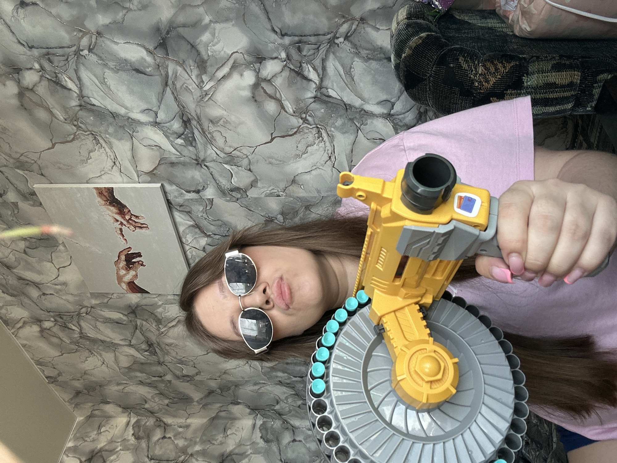 Woman poses with toy gun in playful indoor selfie session