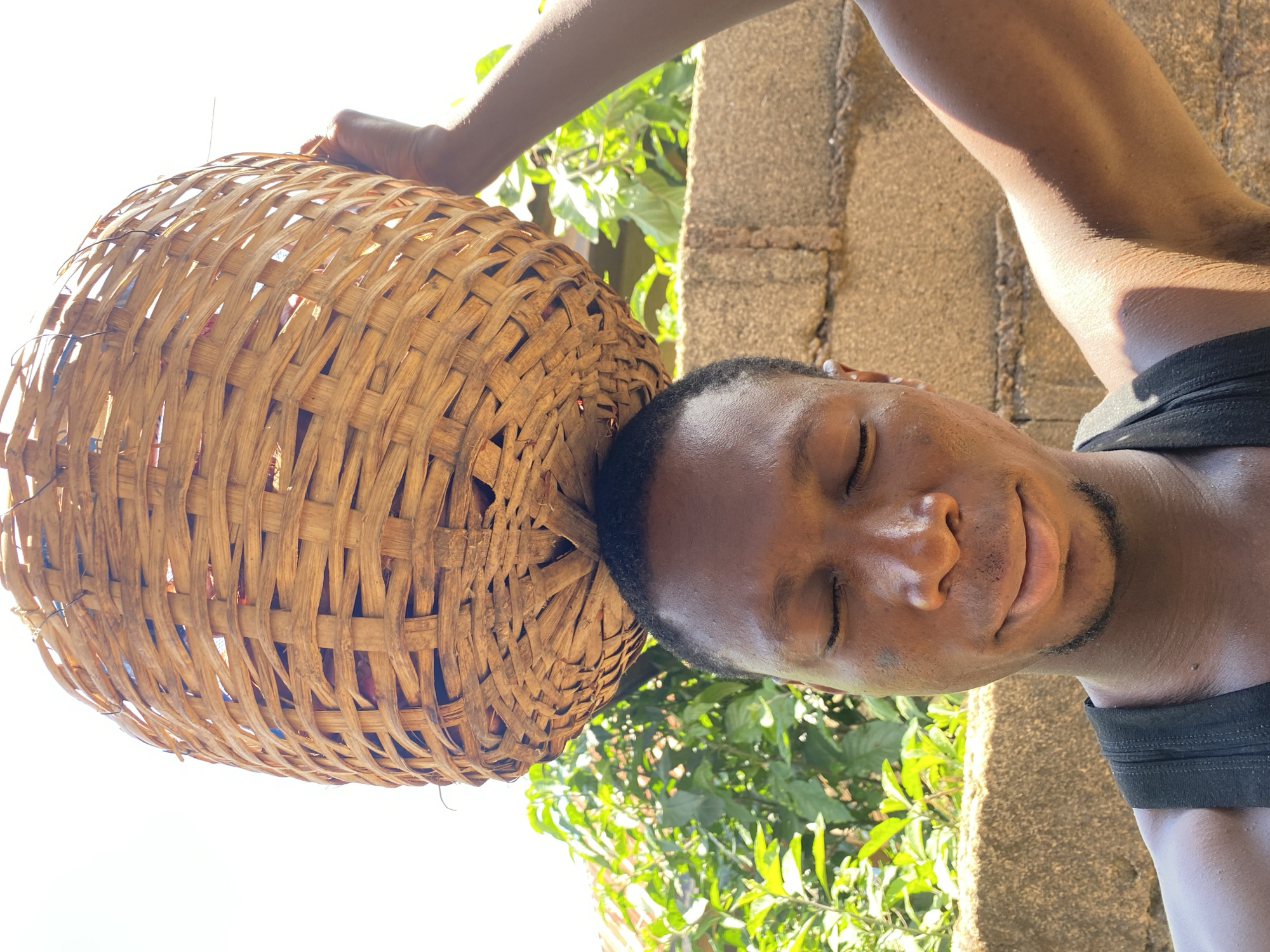 Carrying a large woven basket through Bukuru, Nigeria