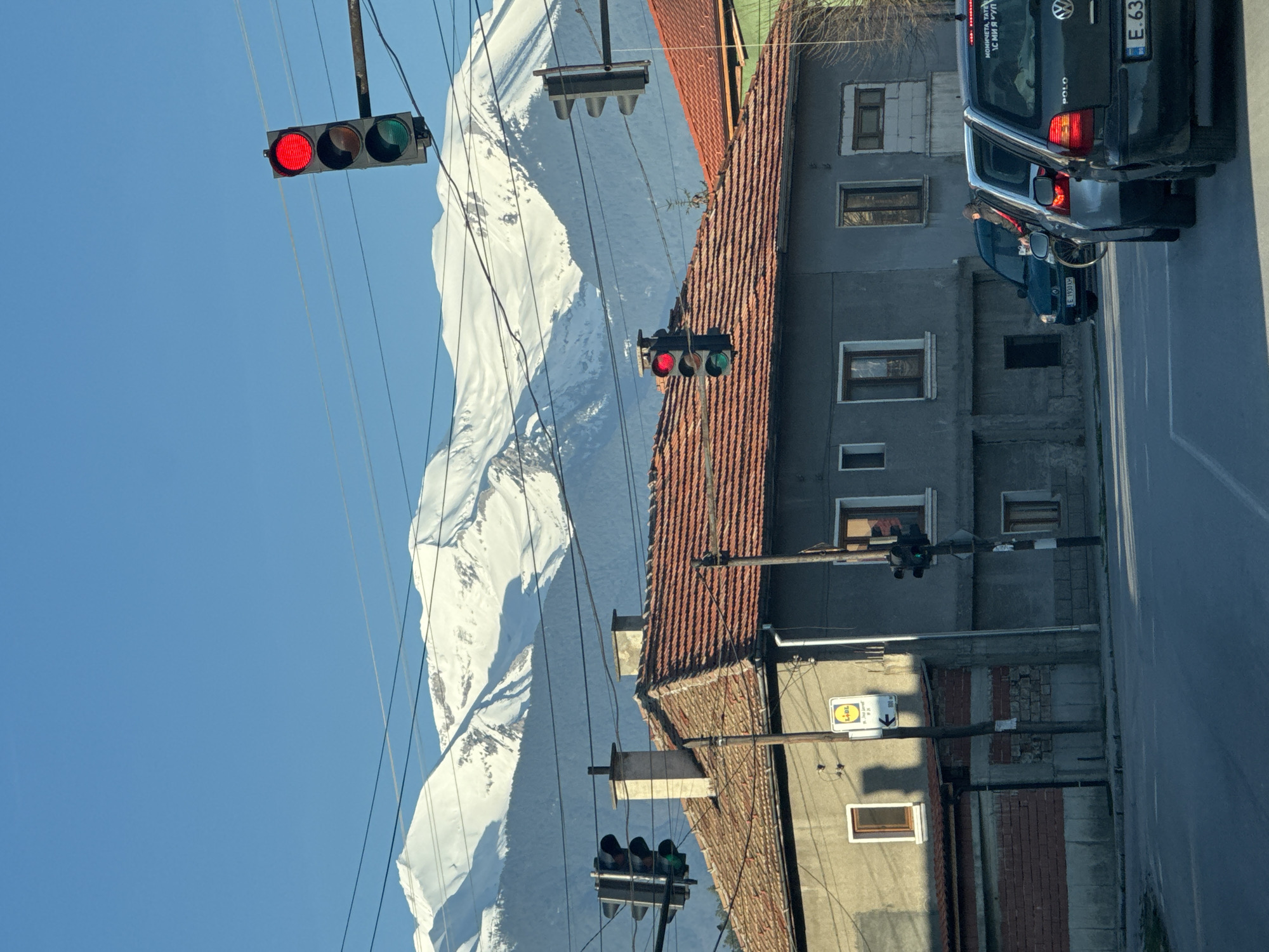 Morning street view captures snowy mountains behind Razlog traffic lights
