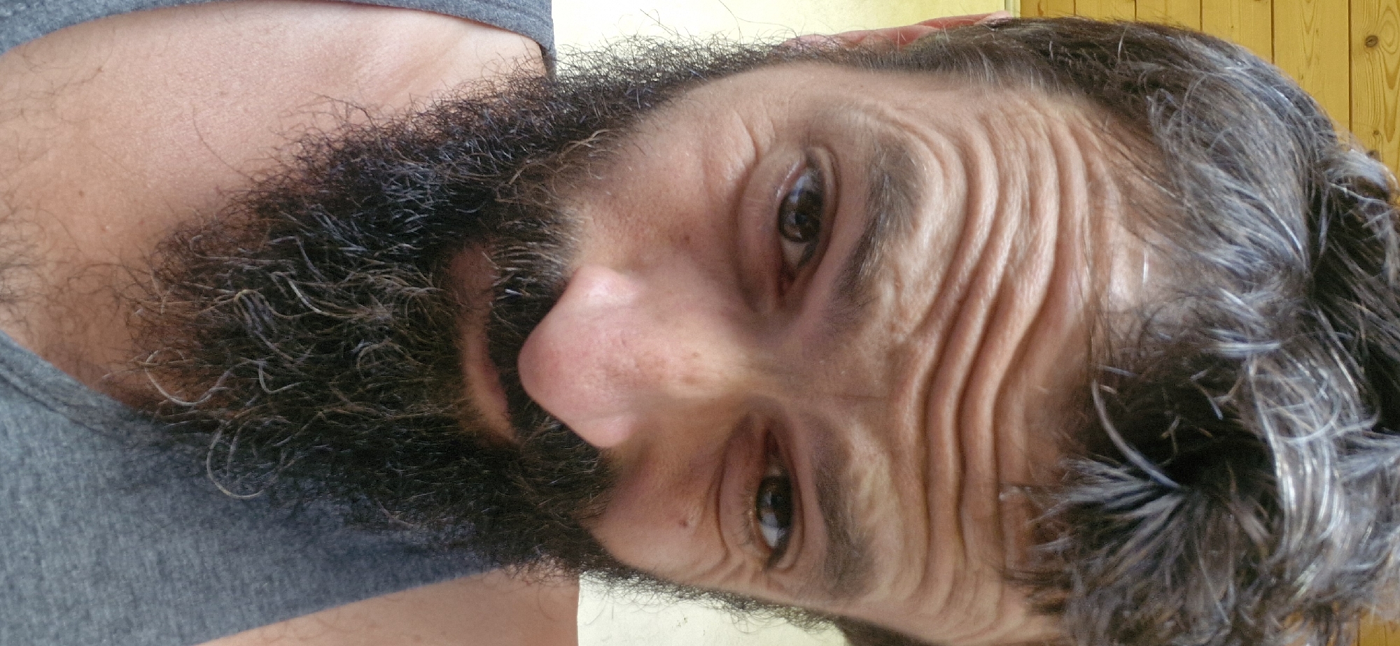 Bearded selfie series: expressive close-ups in a gray tank top