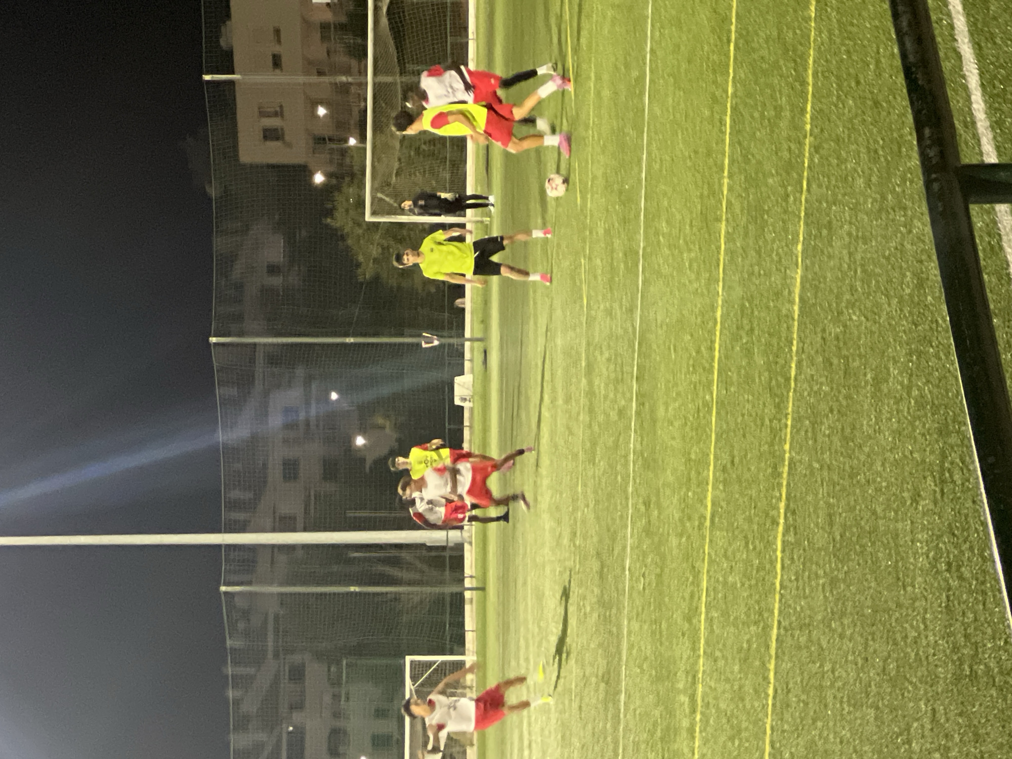 Nighttime football in Albufeira, watched from a wooden bench