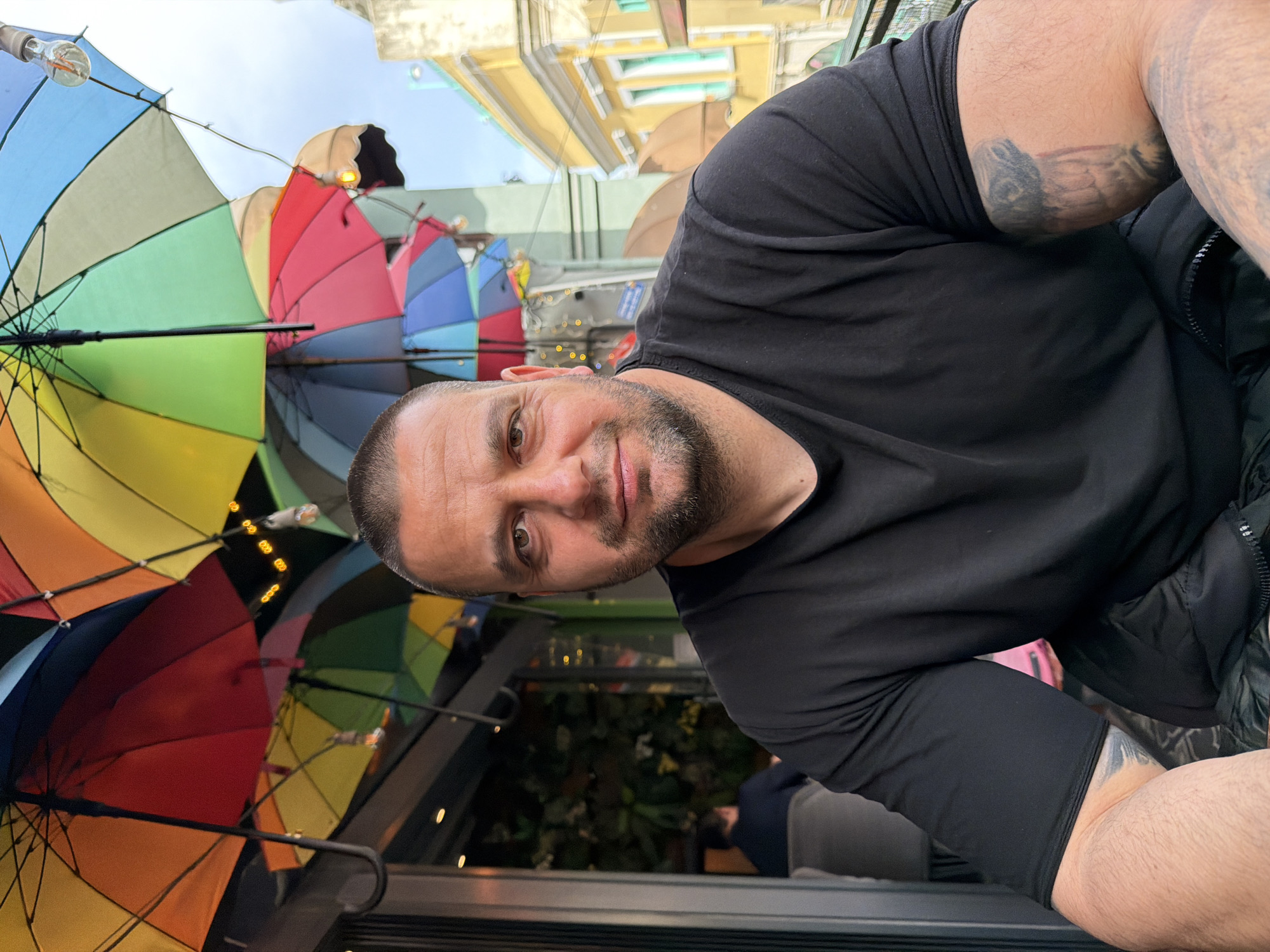 Tattooed man spotted near colorful umbrella display in Beyoğlu