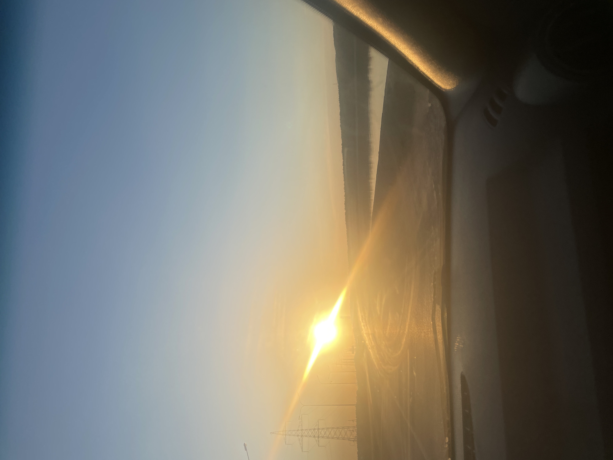 Vehicle passenger captures sunny landscape view with power lines