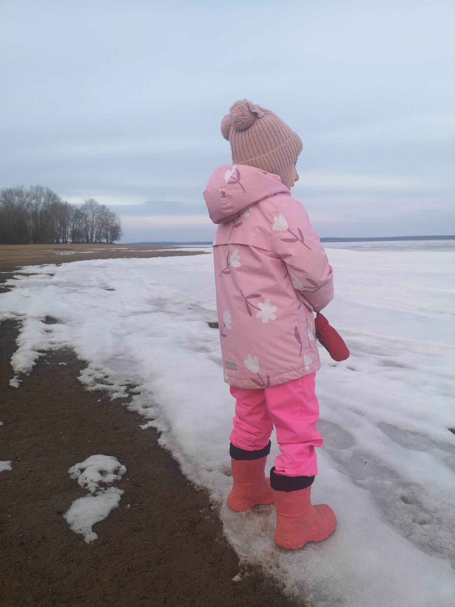 Mother and child explore frozen Russian shoreline in spring