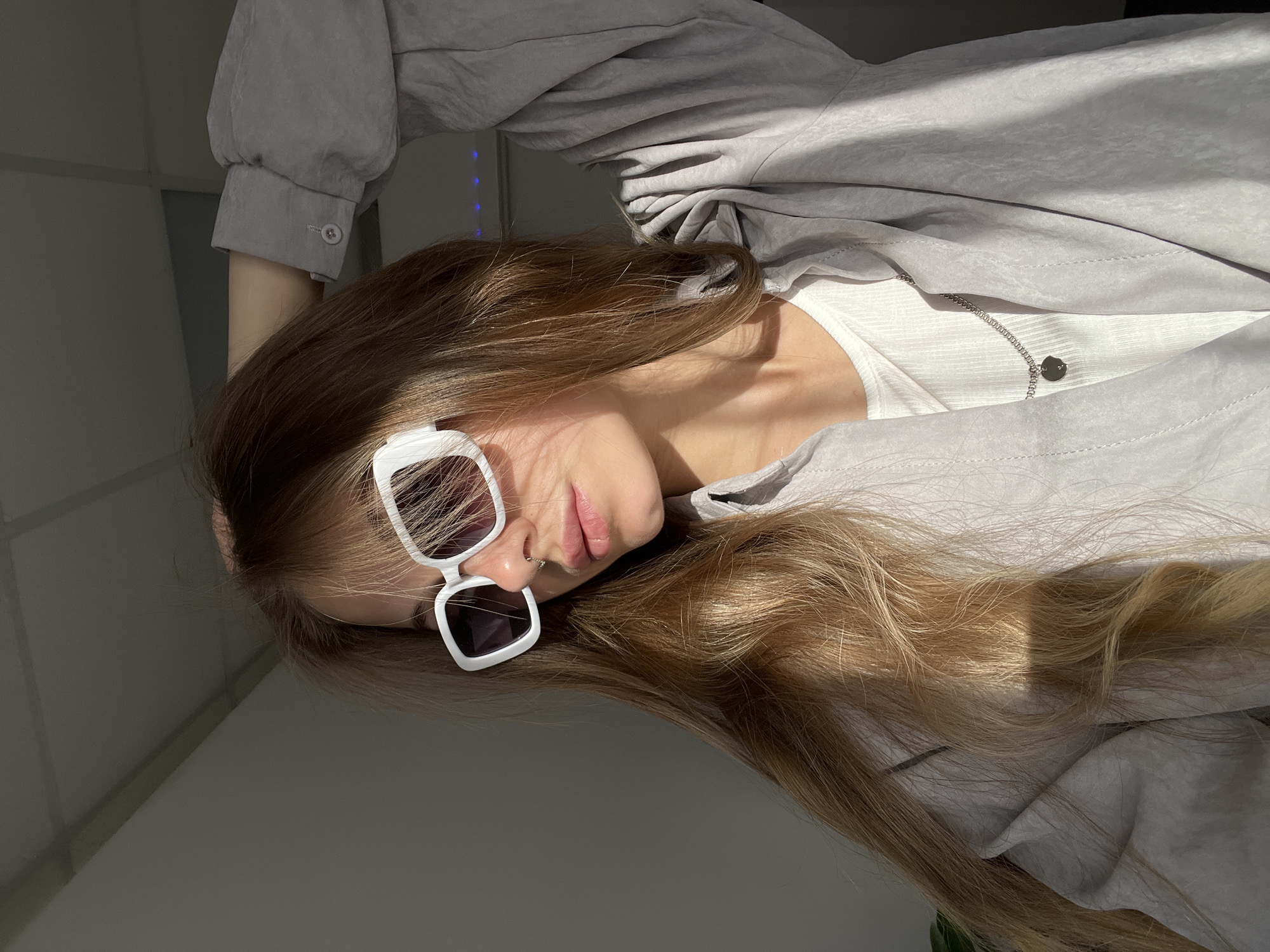Woman takes selfies in sunlit room in Foki, Russia