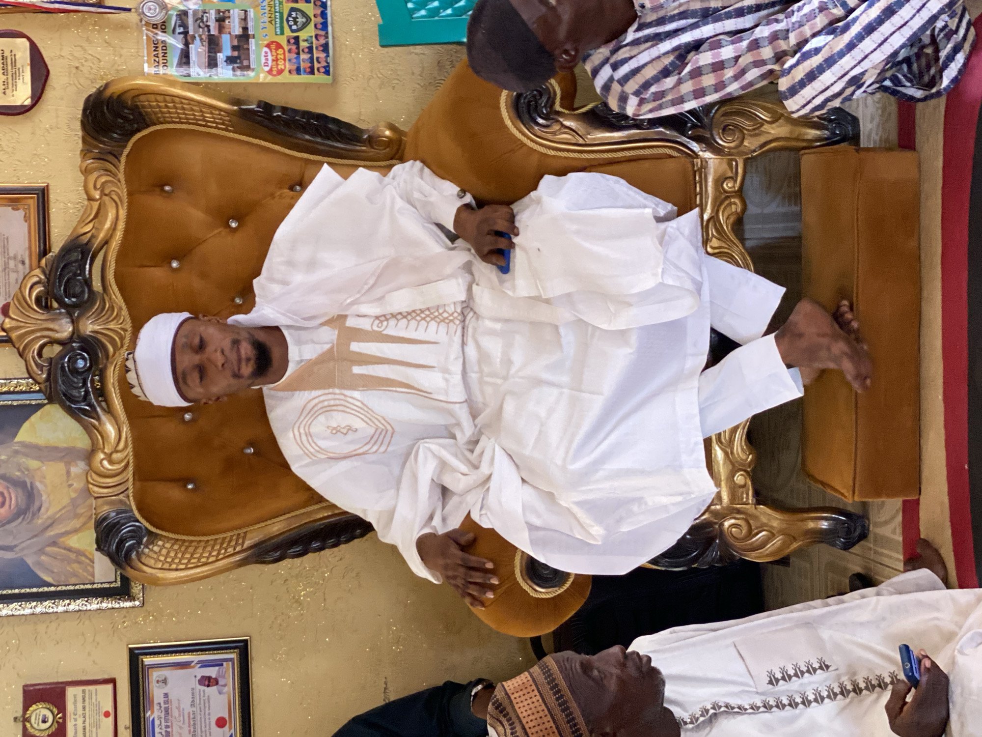 Man in traditional attire rests in ornate chair in Nigeria
