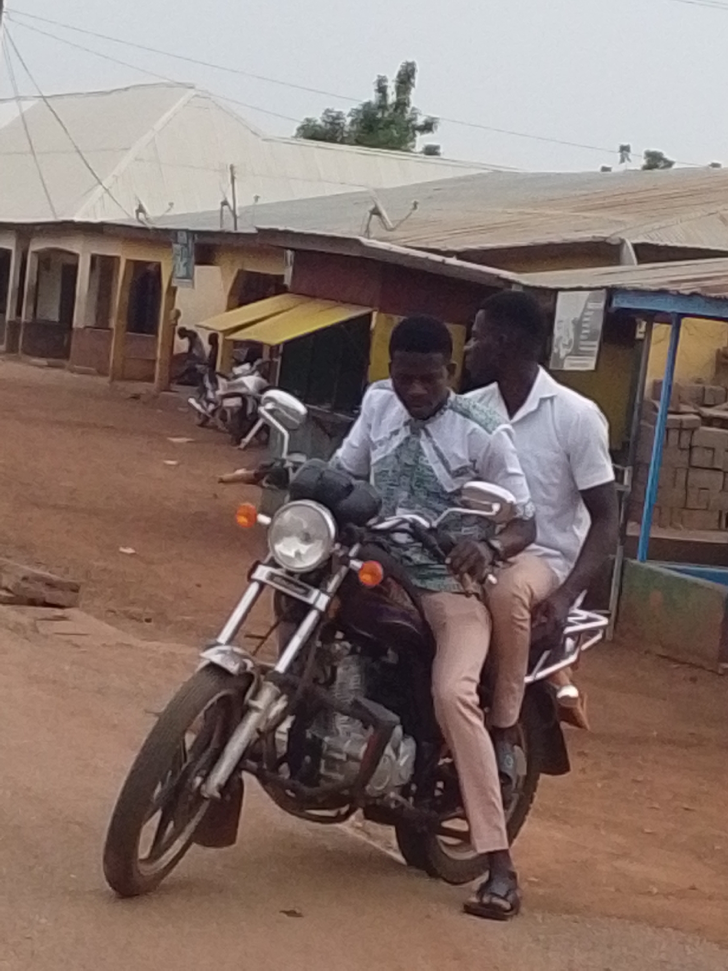 Two men ride motorcycle together in Tamale Ghana