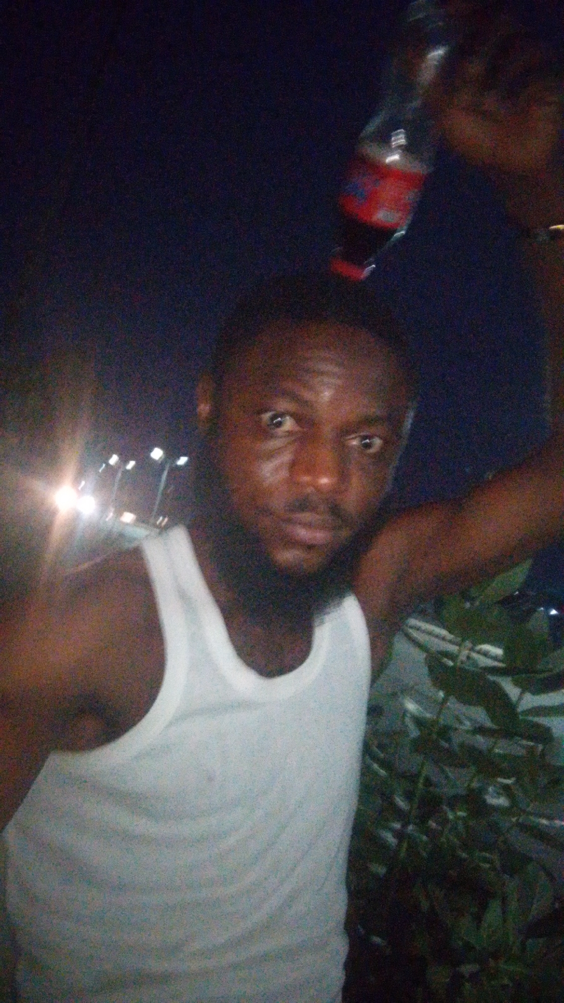 Man poses with beverages during evening photo session in Lokoja