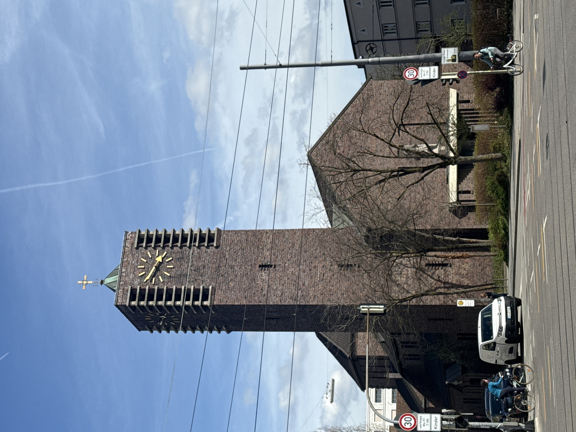 Munich church tower observed under cloudy skies with contrails