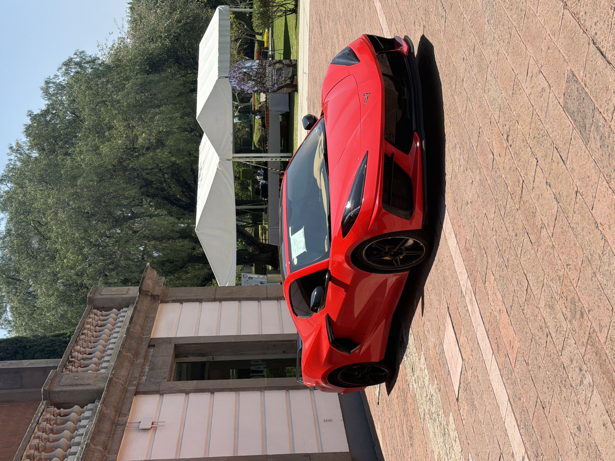 Red sports car spotted parked near building with tents
