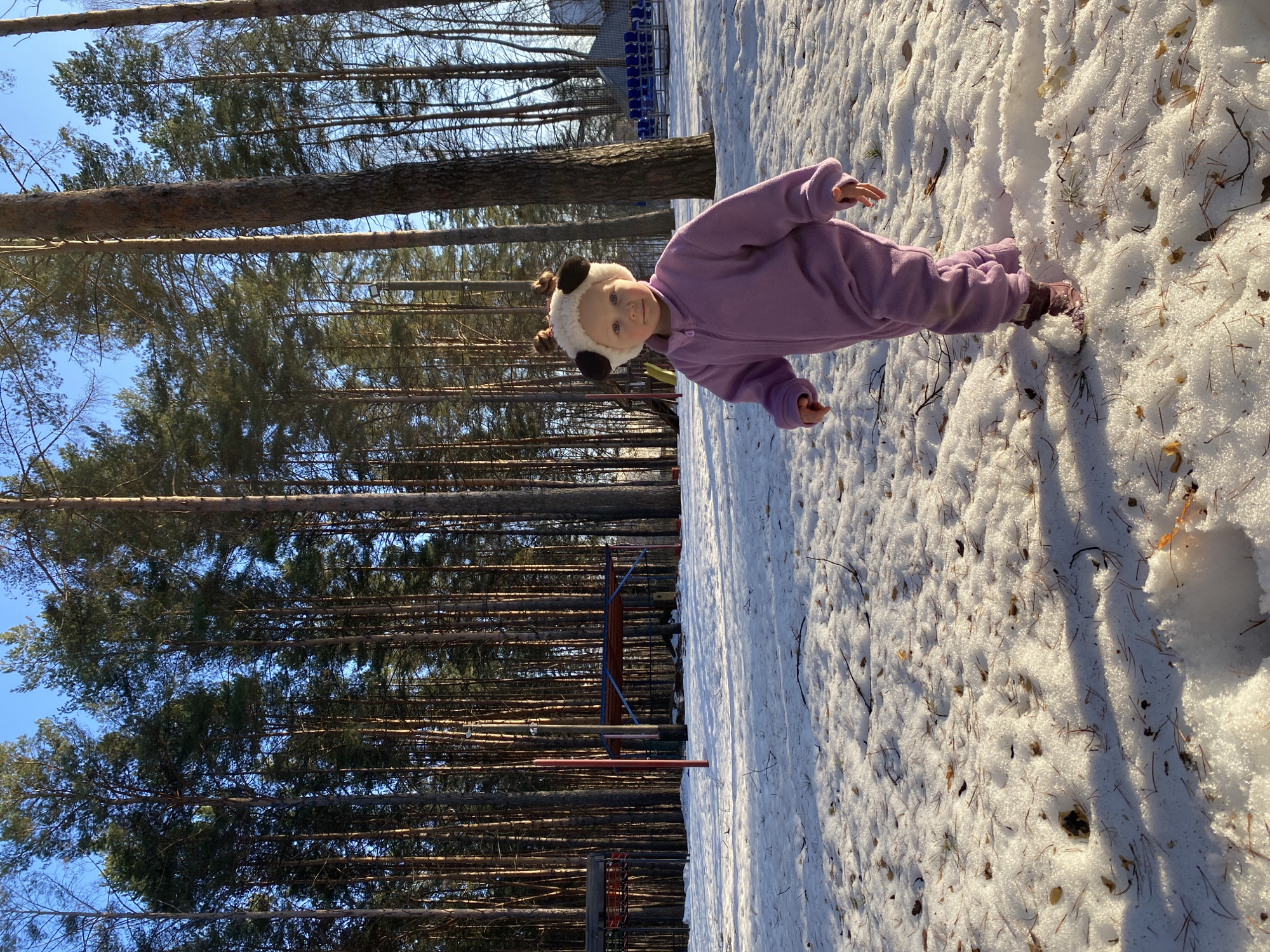 Child plays in snow wearing panda hat in Russian woods