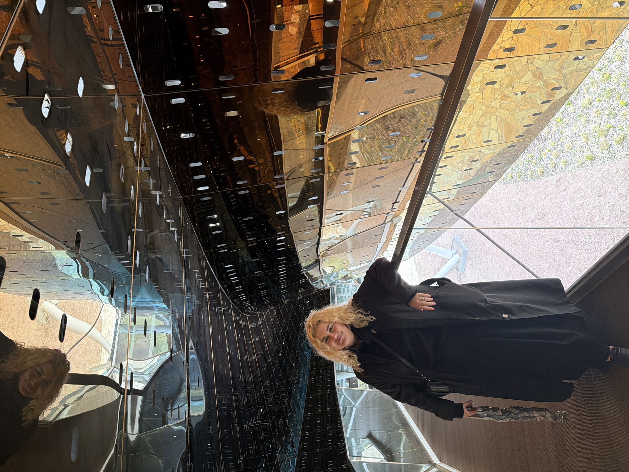 Woman in black observed in reflective space in Moscow