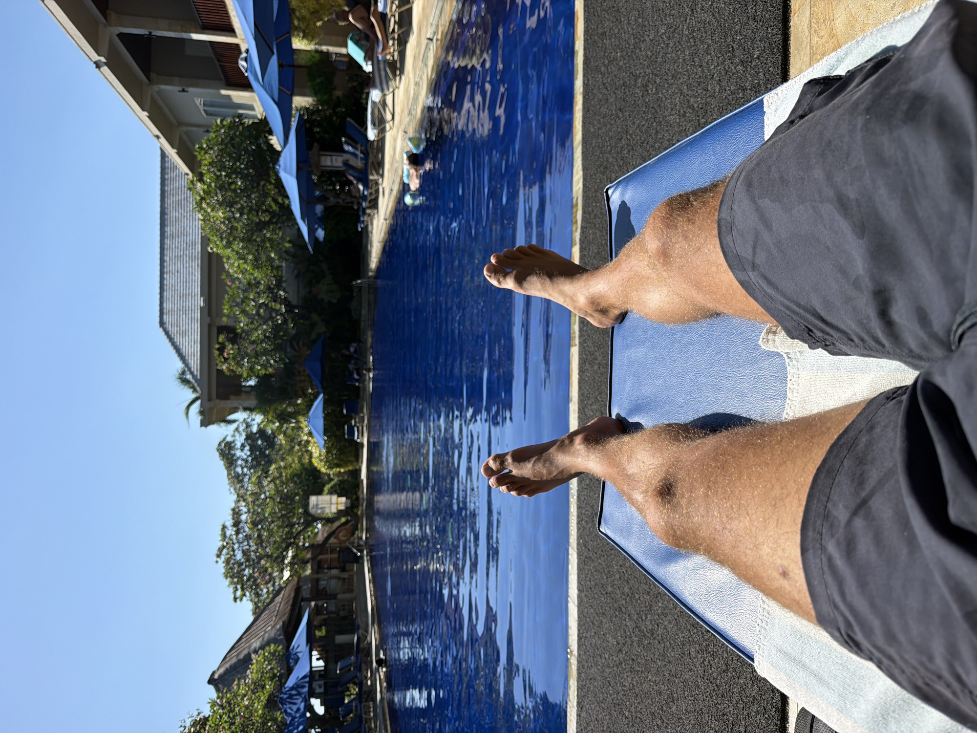 Poolside relaxation at a Buleleng resort, legs up.
