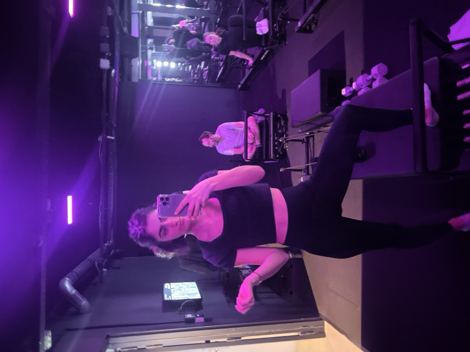 Woman takes selfie in purple-lit Paris fitness studio