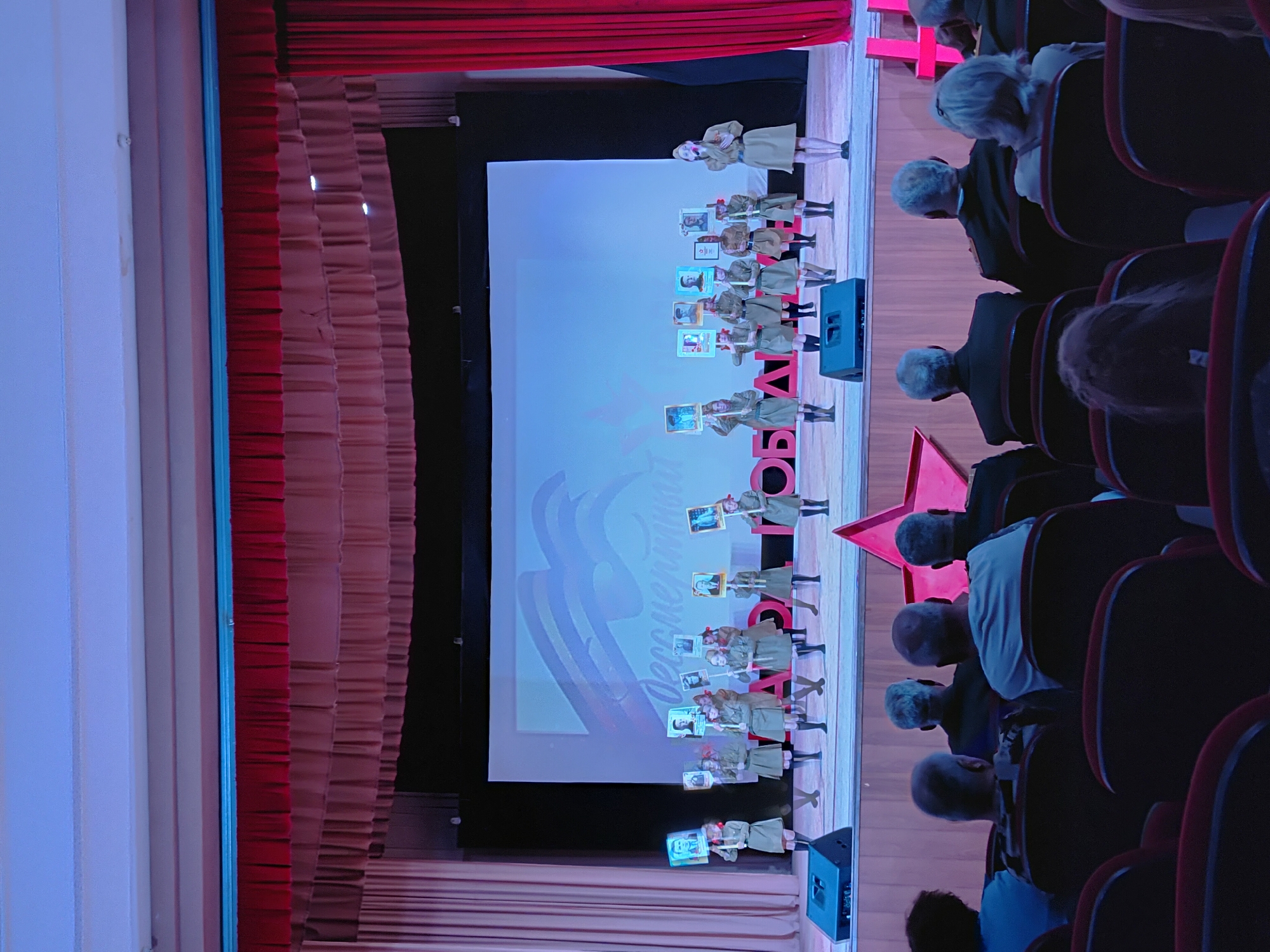 Children perform commemorative theater presentation with framed pictures