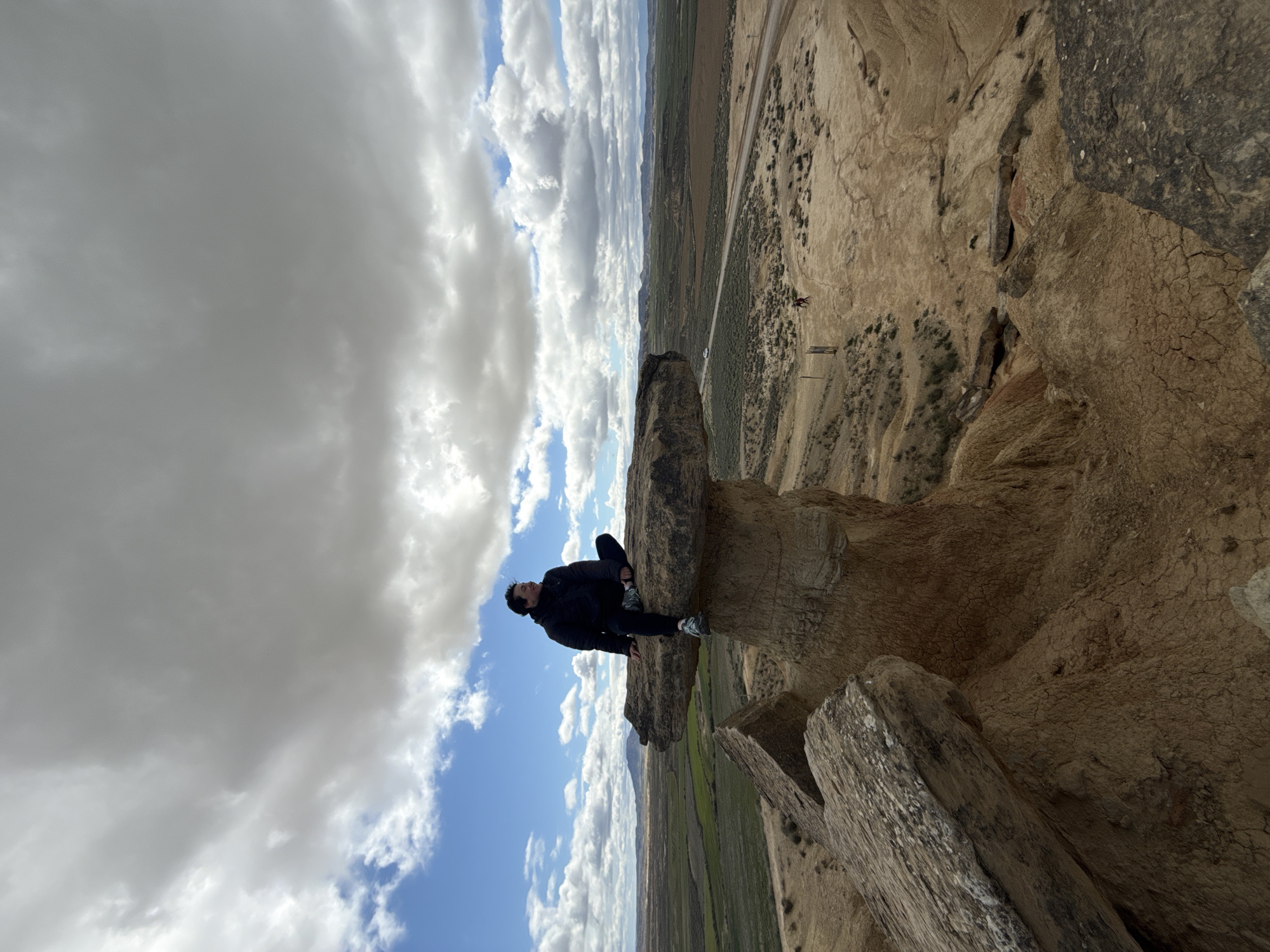 Visitor sits on mushroom rock formation in Bardenas Reales