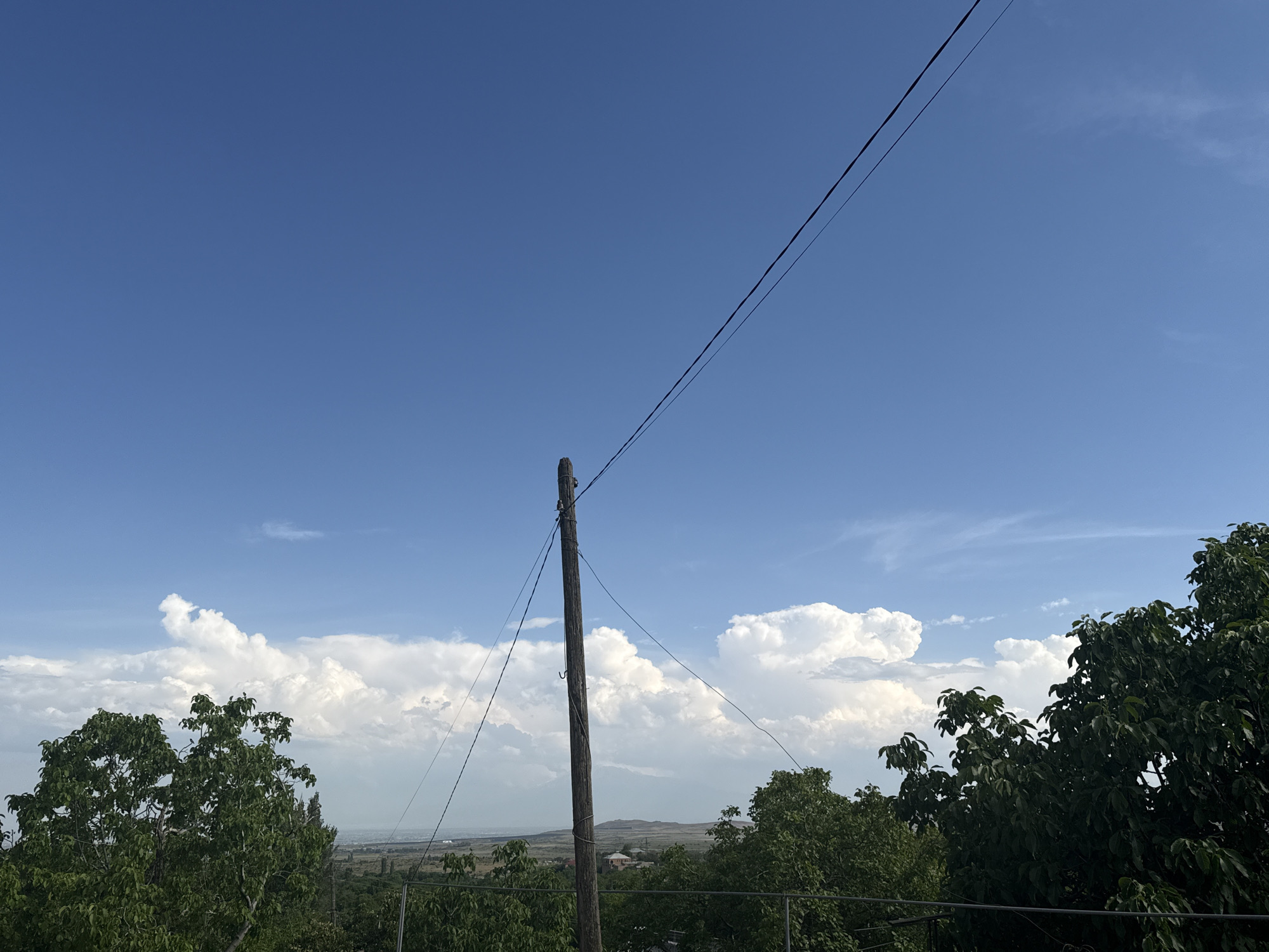 Utility pole stands against blue sky with white clouds