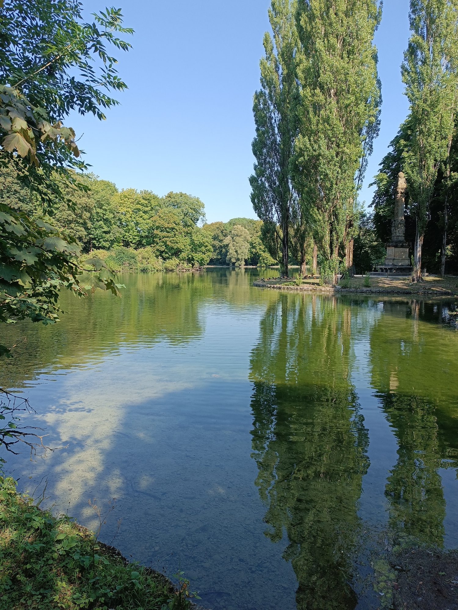Lakeside monument and waterfall in a Munich park