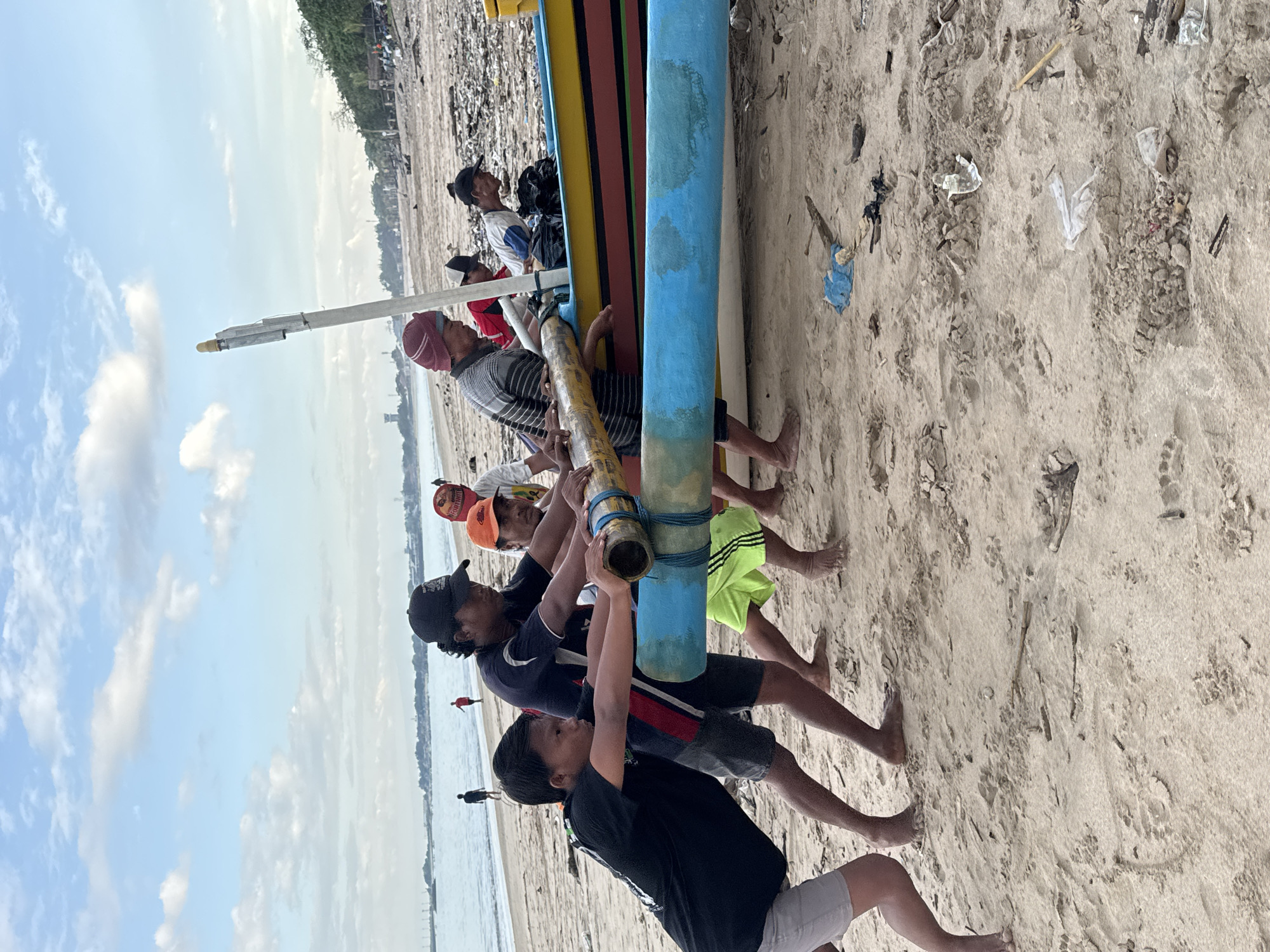 Men move traditional painted boat on Kuta beach